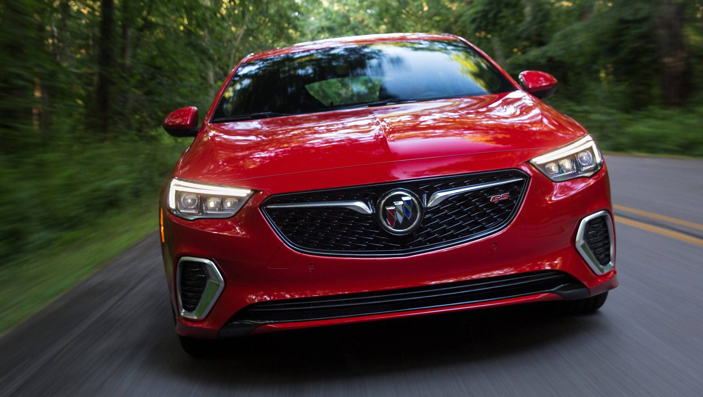 Buick 桌布 壁紙 — 一輛鮮紅色的別克Regal GS在樹林環繞的道路上疾馳，周圍環境呈現動態模糊效果。