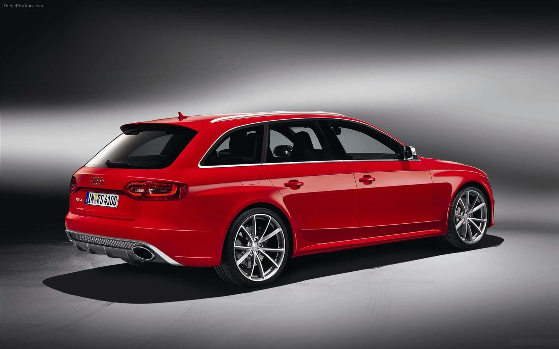 Audi Rs5 桌布 壁紙 — 一輛鮮紅色的奧迪 RS4 Avant 旅行車在漸變灰色背景下的攝影棚燈光中閃閃發光。