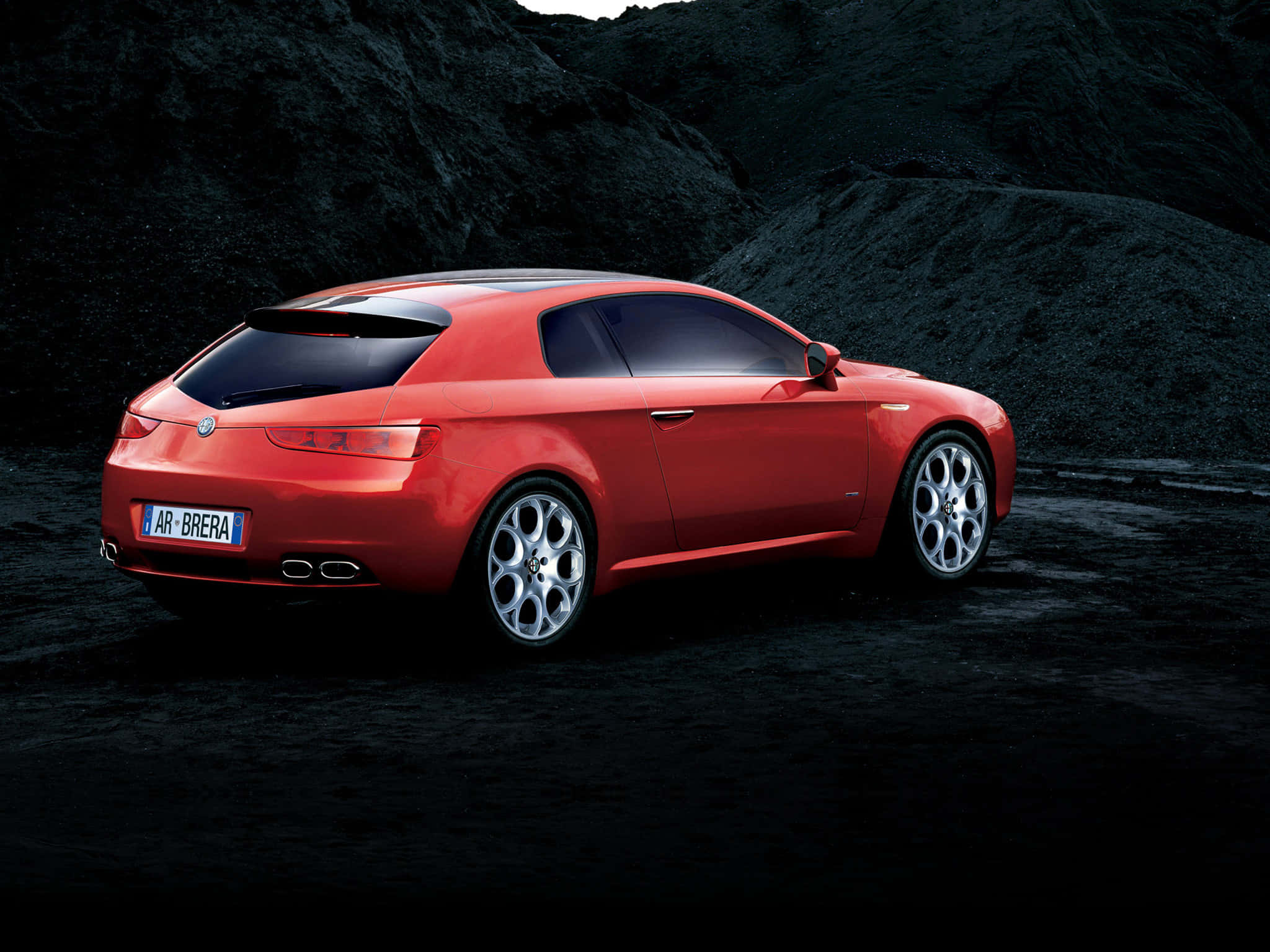 Alfa Romeo Brera 桌布 壁紙 — 一輛鮮紅色的愛快羅密歐 Brera 跑車在戲劇性燈光下，於黑色火山岩背景下閃閃發光。