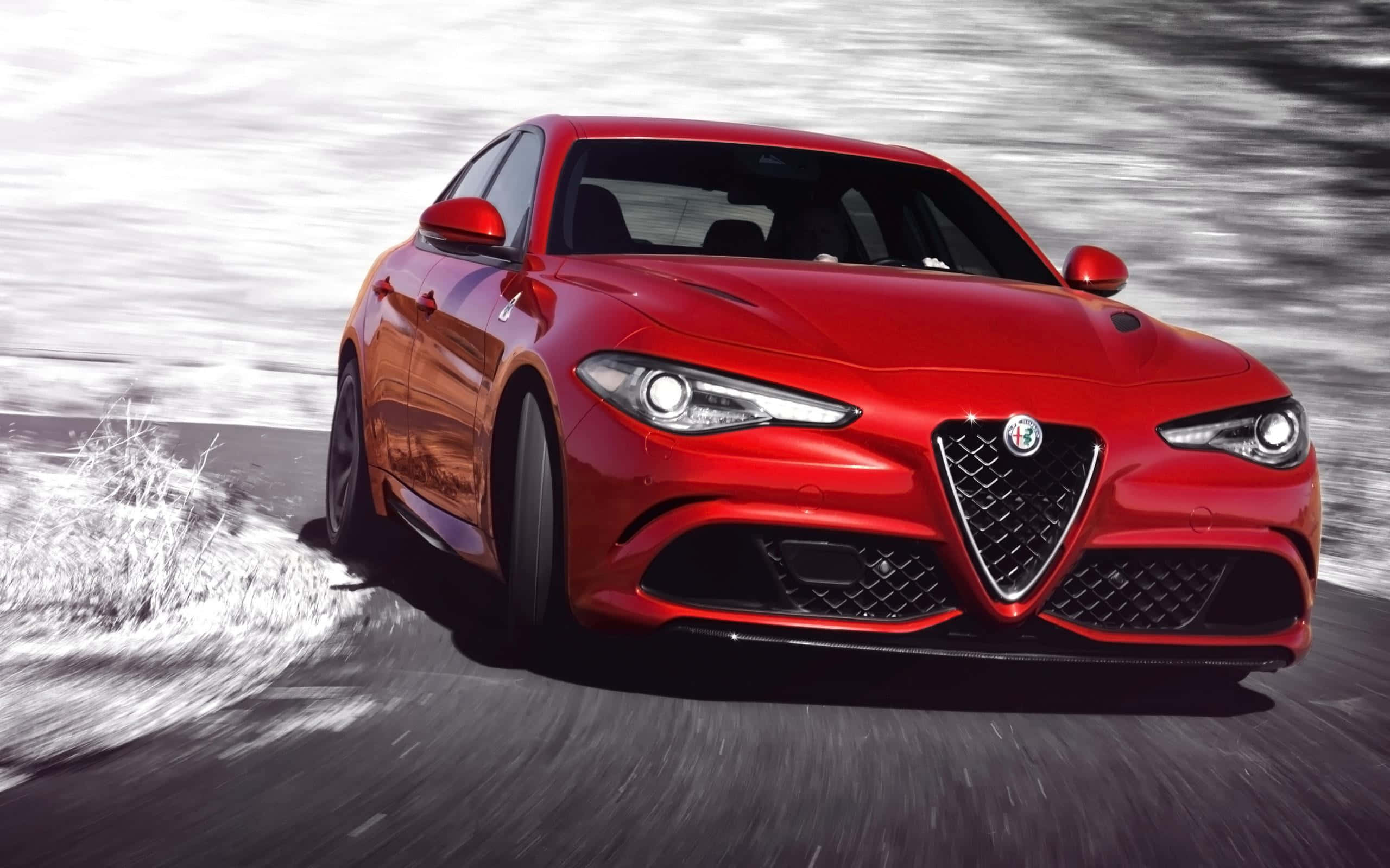 Alfa Romeo Giulia 桌布 壁紙 — 一輛鮮紅色的愛快羅密歐跑車在雪路上疾馳，動態模糊效果強調其動感。