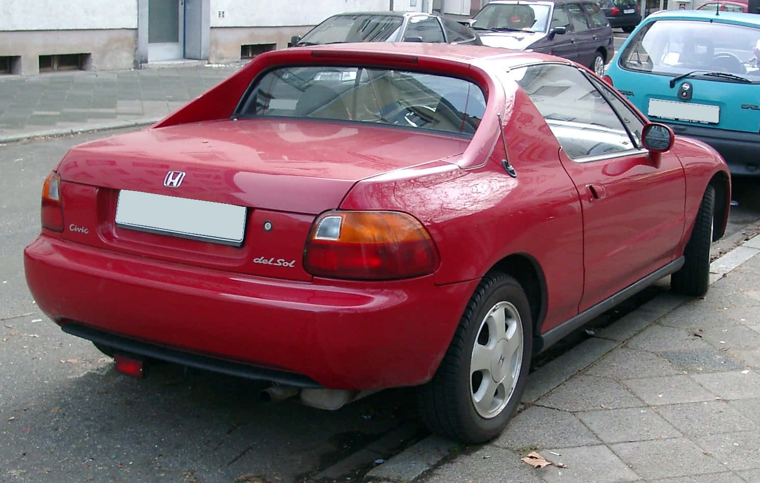 Honda Civic Del Sol 桌布 壁紙 — 一輛鮮紅色的本田Civic del Sol停放在鋪砌的街道上，附近有其他車輛。