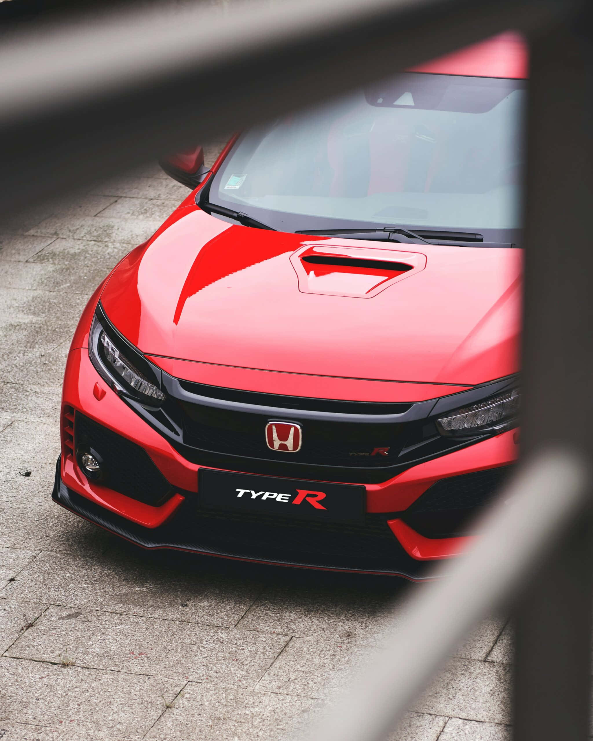 Red Car 桌布 壁紙 — 一輛鮮紅色的本田思域Type R跑車，透過金屬框架在鋪砌表面上觀看。