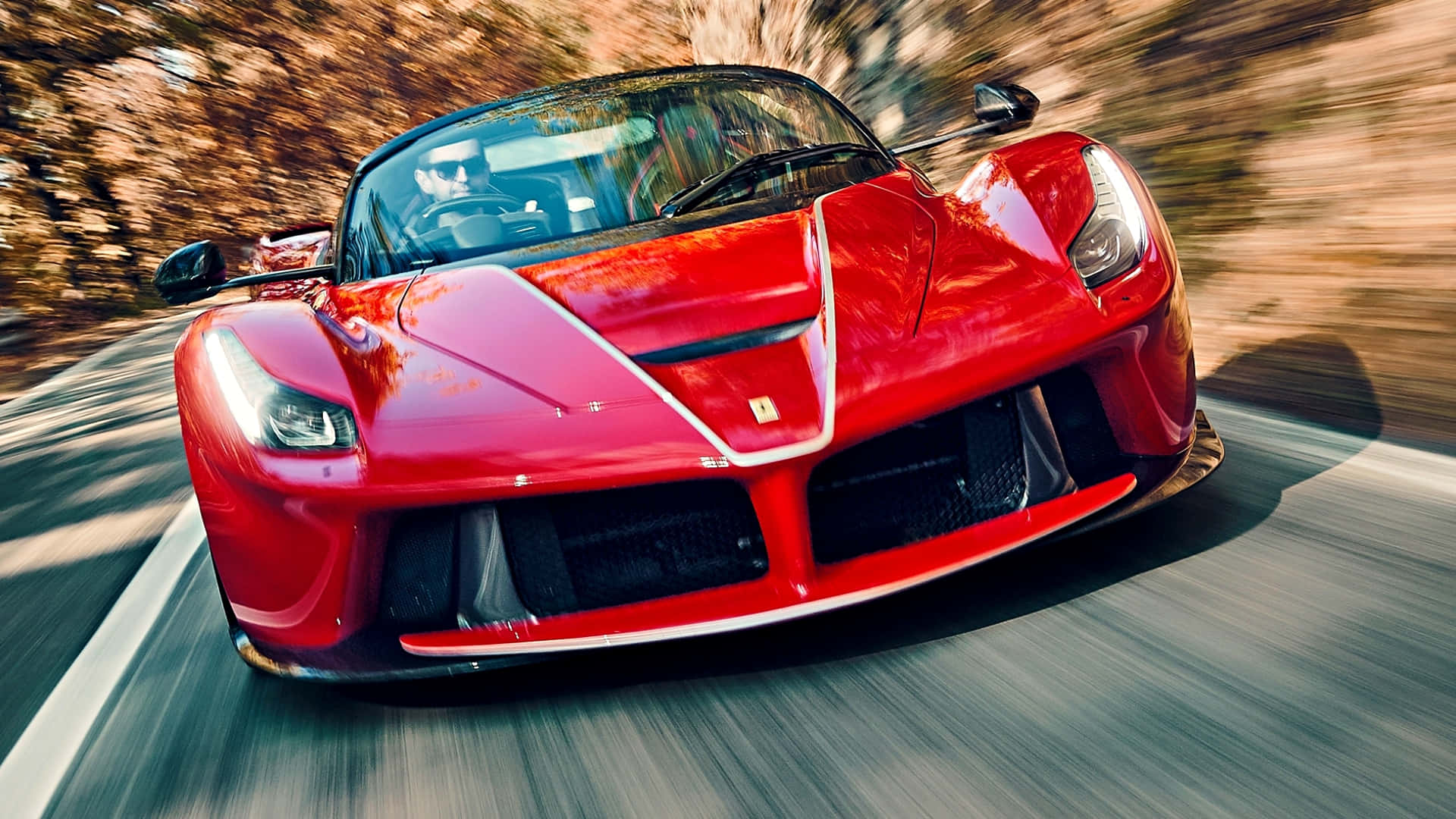 法拉利 桌布 壁紙 — 一輛鮮紅色的法拉利 LaFerrari 在蜿蜒的道路上飛馳，模糊的秋葉掠過。