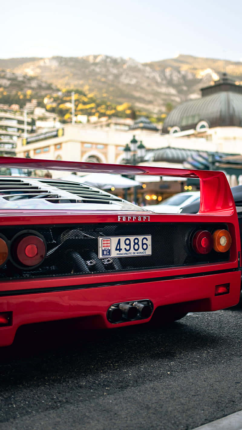 Vintage Ferrari 桌布 壁紙 — 一輛鮮紅色的法拉利F40停泊在陽光明媚的摩納哥街道上，背景是柔焦的山脈和建築物。