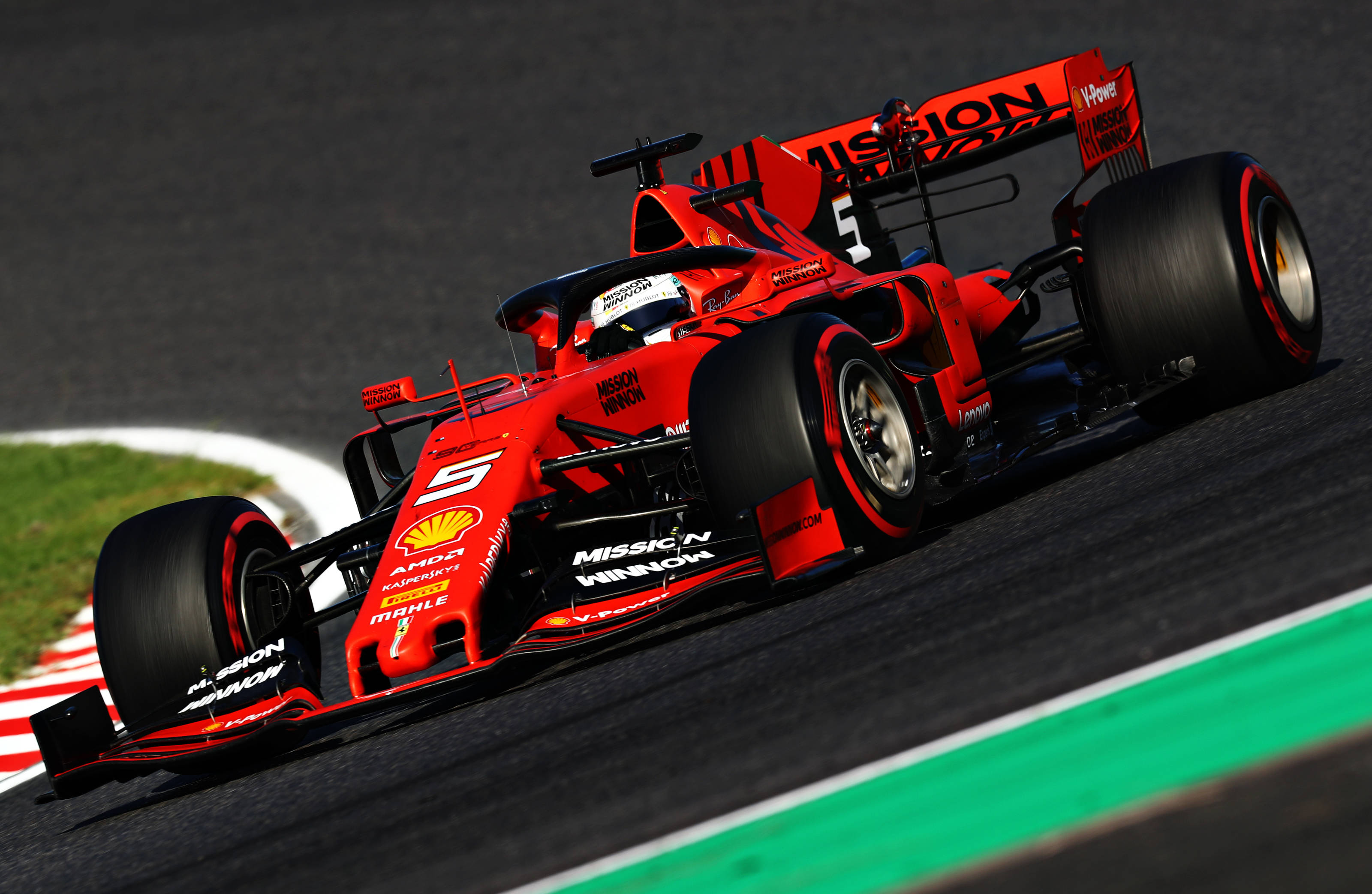 Formula One 桌布 壁紙 — 一輛鮮紅色的法拉利一級方程式賽車在明亮的日光下，在帶有綠色和白色路緣的賽道上高速過彎。