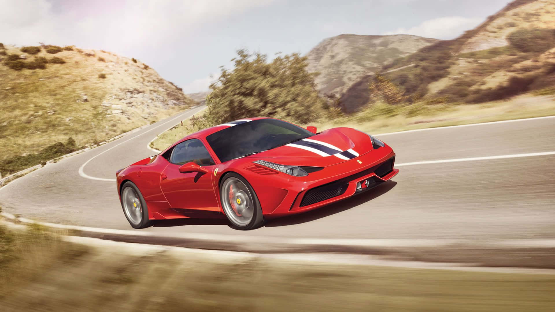 Ferrari 458 Speciale 桌布 壁紙 — 一輛鮮紅色的法拉利在蜿蜒的山路上疾馳，模糊的風景強調了動感。