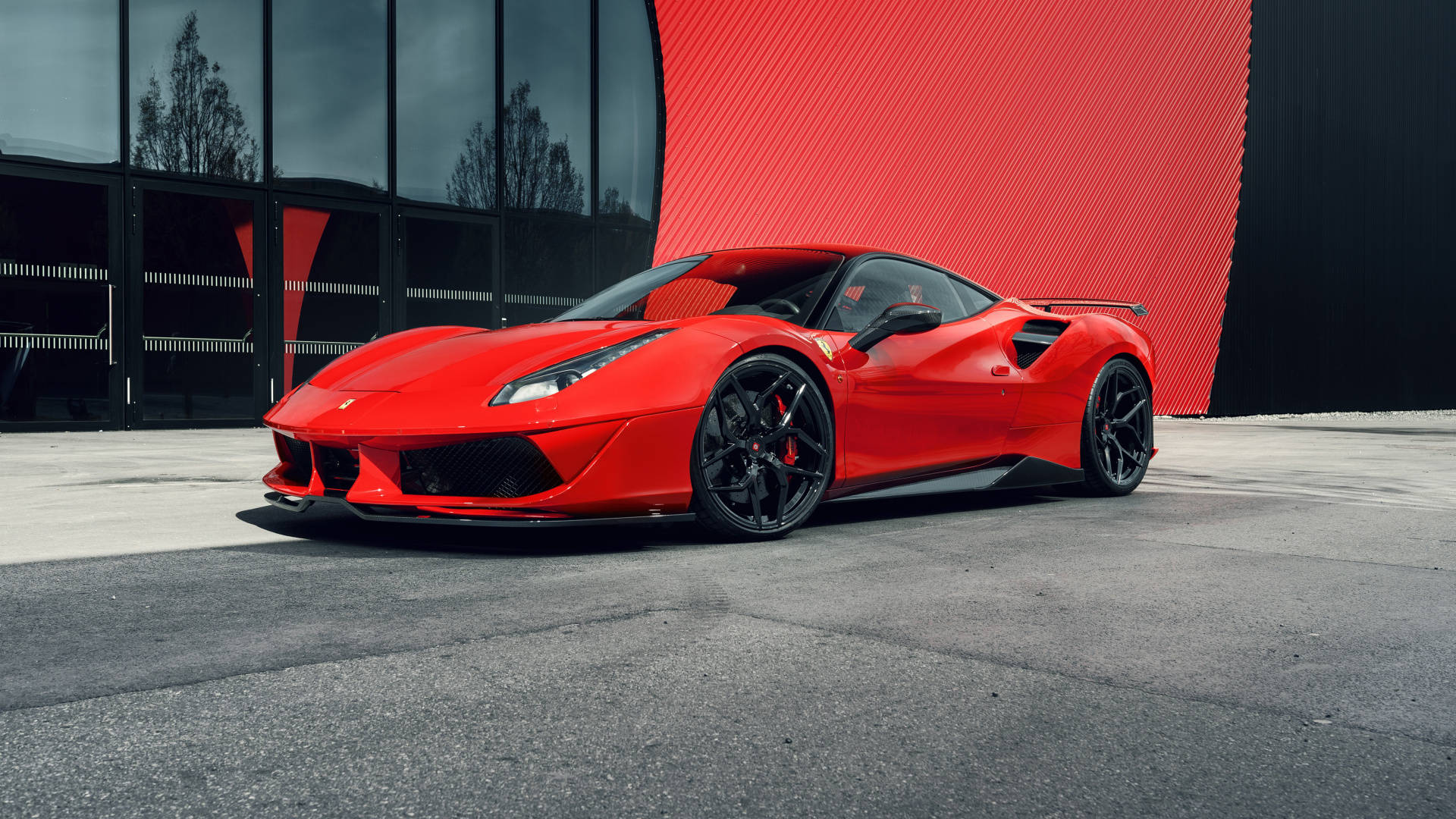 1920x1080 Ferrari 桌布 壁紙 — 一輛鮮紅色的法拉利跑車停放在現代建築前的混凝土上，建築物有醒目的紅色和黑色牆壁。