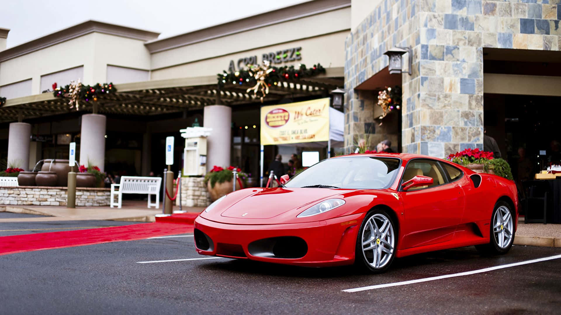 Ferrari F430 桌布 壁紙 — 一輛鮮紅色的法拉利跑車停放在節日裝飾的餐廳外的紅地毯上。