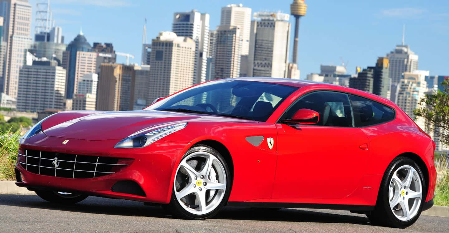 Ferrari Ff 桌布 壁紙 — 一輛鮮紅色的法拉利跑車在明亮的陽光下閃閃發光，停放在現代城市天際線前，高樓大廈林立。