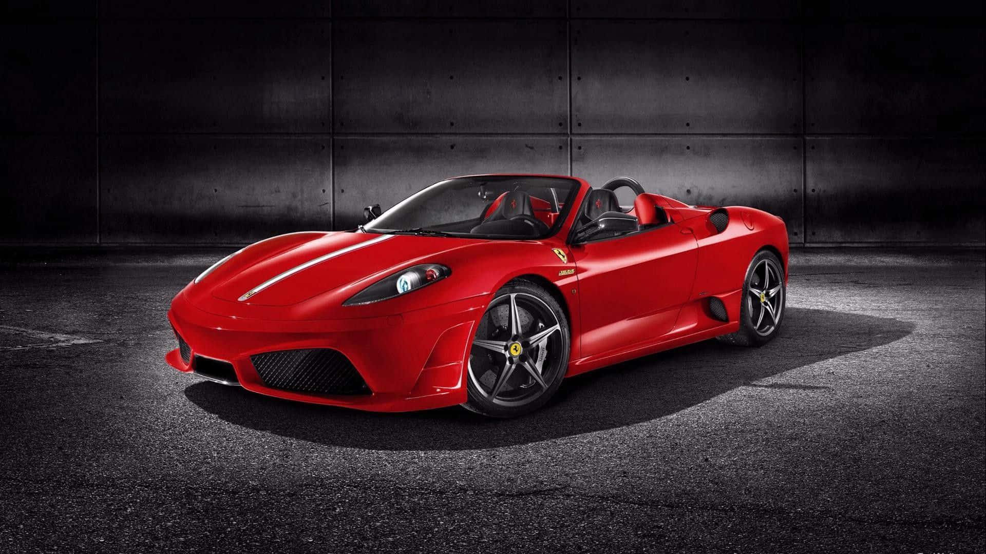 Ferrari F430 桌布 壁紙 — 一輛鮮紅色的法拉利跑車在黑暗的混凝土背景下，在攝影棚燈光下閃閃發光。