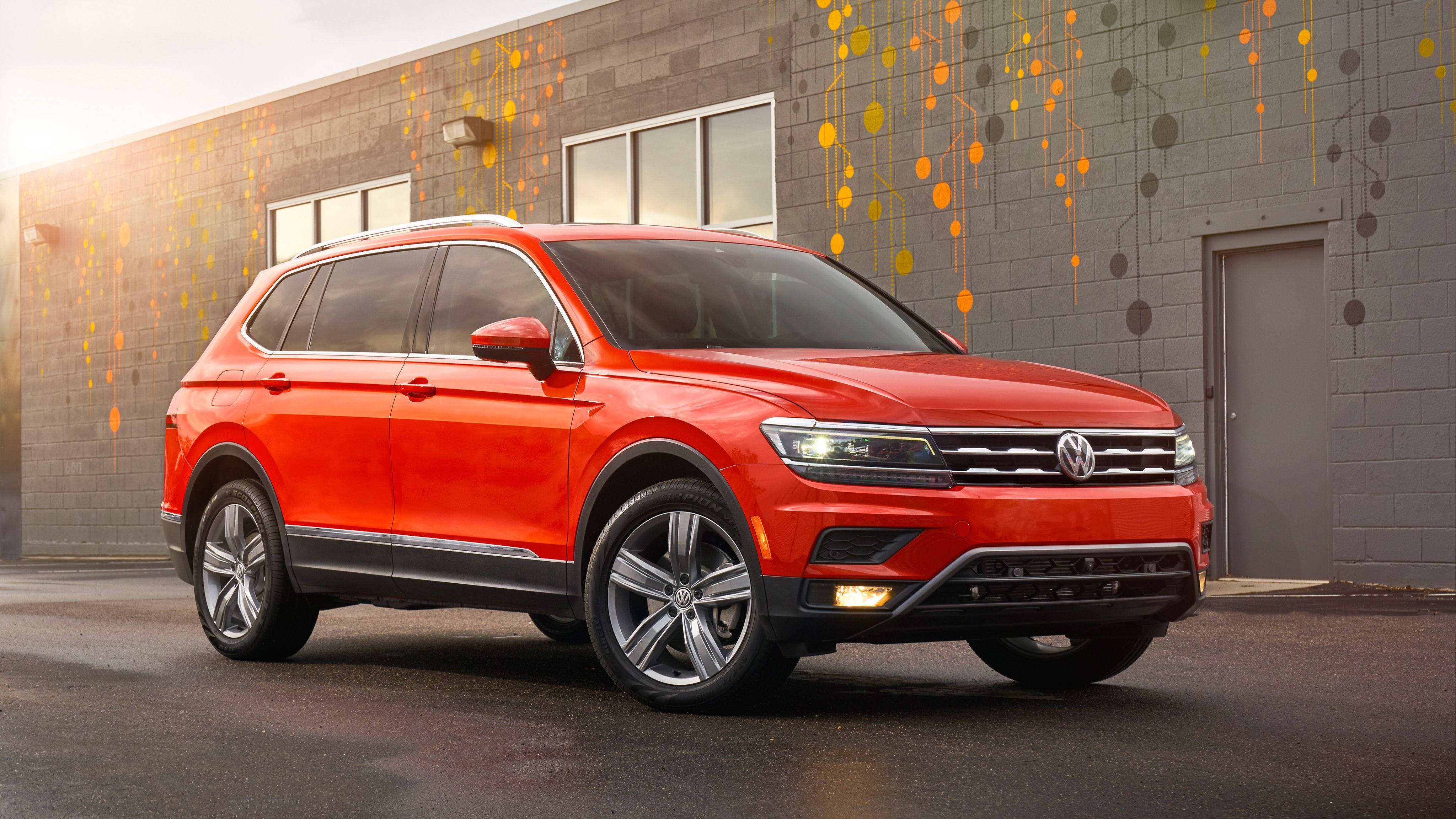 福斯汽車 桌布 壁紙 — 一輛鮮紅色的福斯偉根 Tiguan SUV 停在一棟灰色磚砌建築前，建築上有色彩繽紛的圓形牆壁藝術。