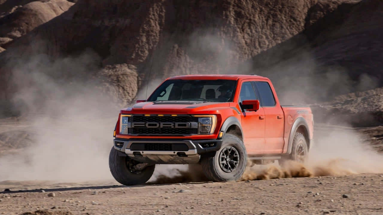 Ford Truck 桌布 壁紙 — 一輛鮮紅色的福特 F-150 Raptor 在塵土飛揚的沙漠峽谷中疾馳，揚起陣陣沙塵。