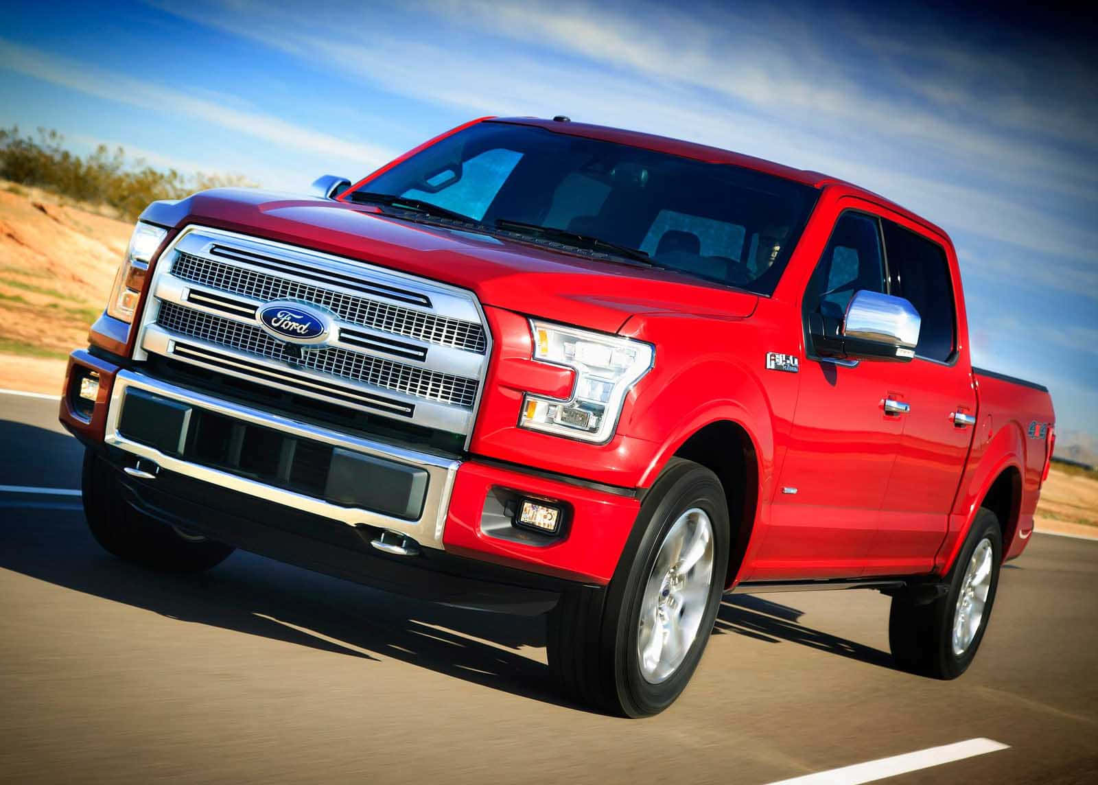 Ford Truck 桌布 壁紙 — 一輛鮮紅色的福特F-150皮卡車在明亮藍天和薄雲下，沿著沙漠高速公路飛馳。