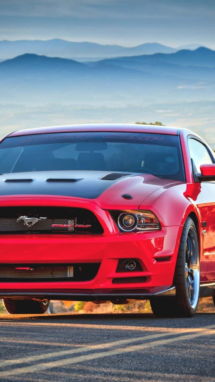 桌布 壁紙 — 一輛鮮紅色的福特野馬Shelby GT500停泊在陽光明媚的道路上，背景是霧氣繚繞的山巒。