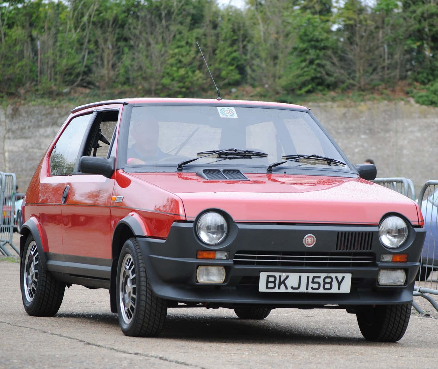 Fiat Ritmo 桌布 壁紙 — 一輛鮮紅色的經典Fiat 126p自豪地停在鋪砌的道路上，背景有綠樹和石牆。