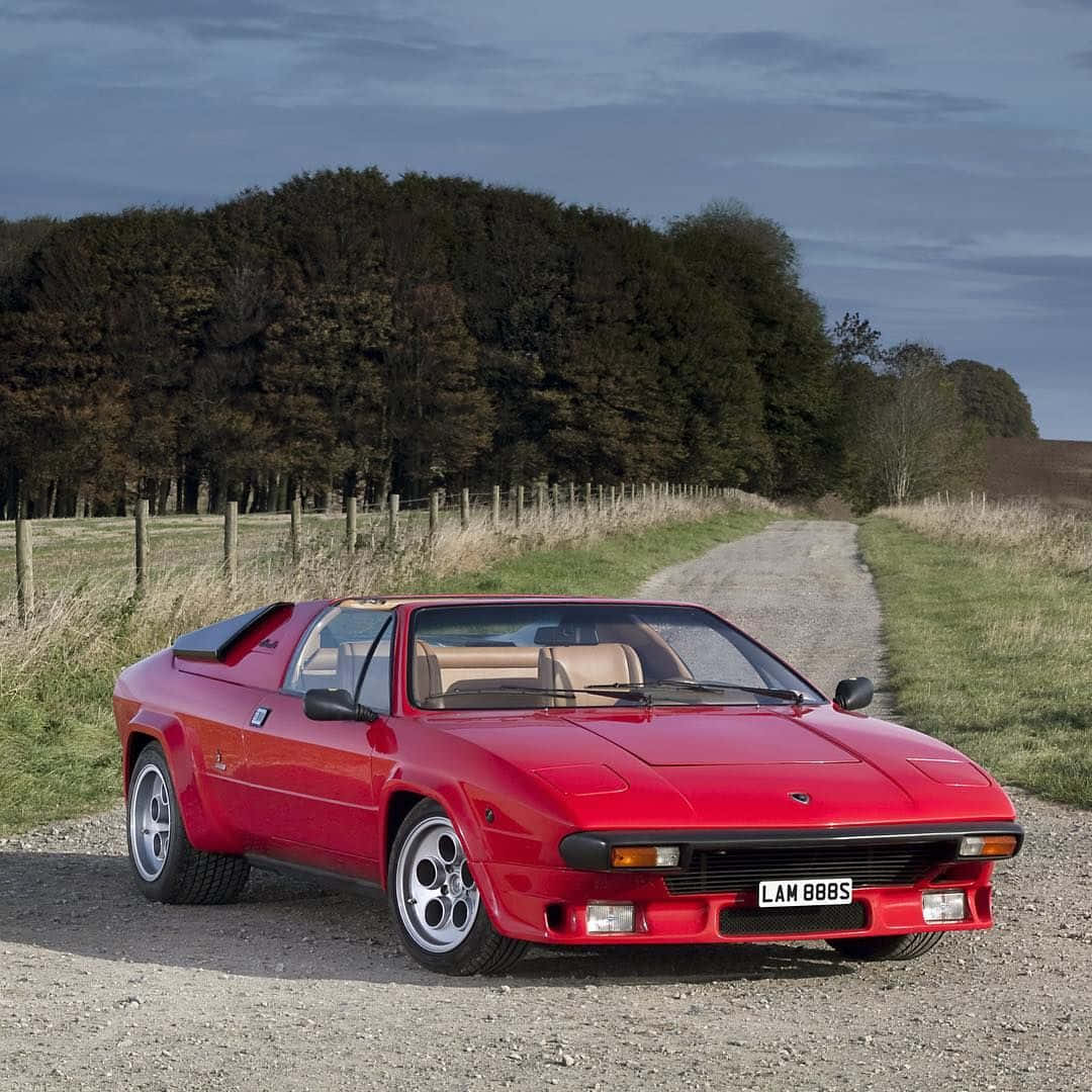 Lamborghini Silhouette 桌布 壁紙 — 一輛鮮紅色的經典跑車停泊在鄉村碎石路上，背景有樹木和田野。