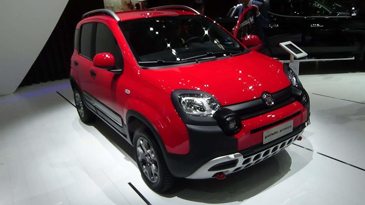 Fiat Panda 桌布 壁紙 — 一輛鮮紅色的菲亞特 Panda Cross SUV 在白色平台上，於明亮的展覽燈光下閃閃發光，車門敞開。