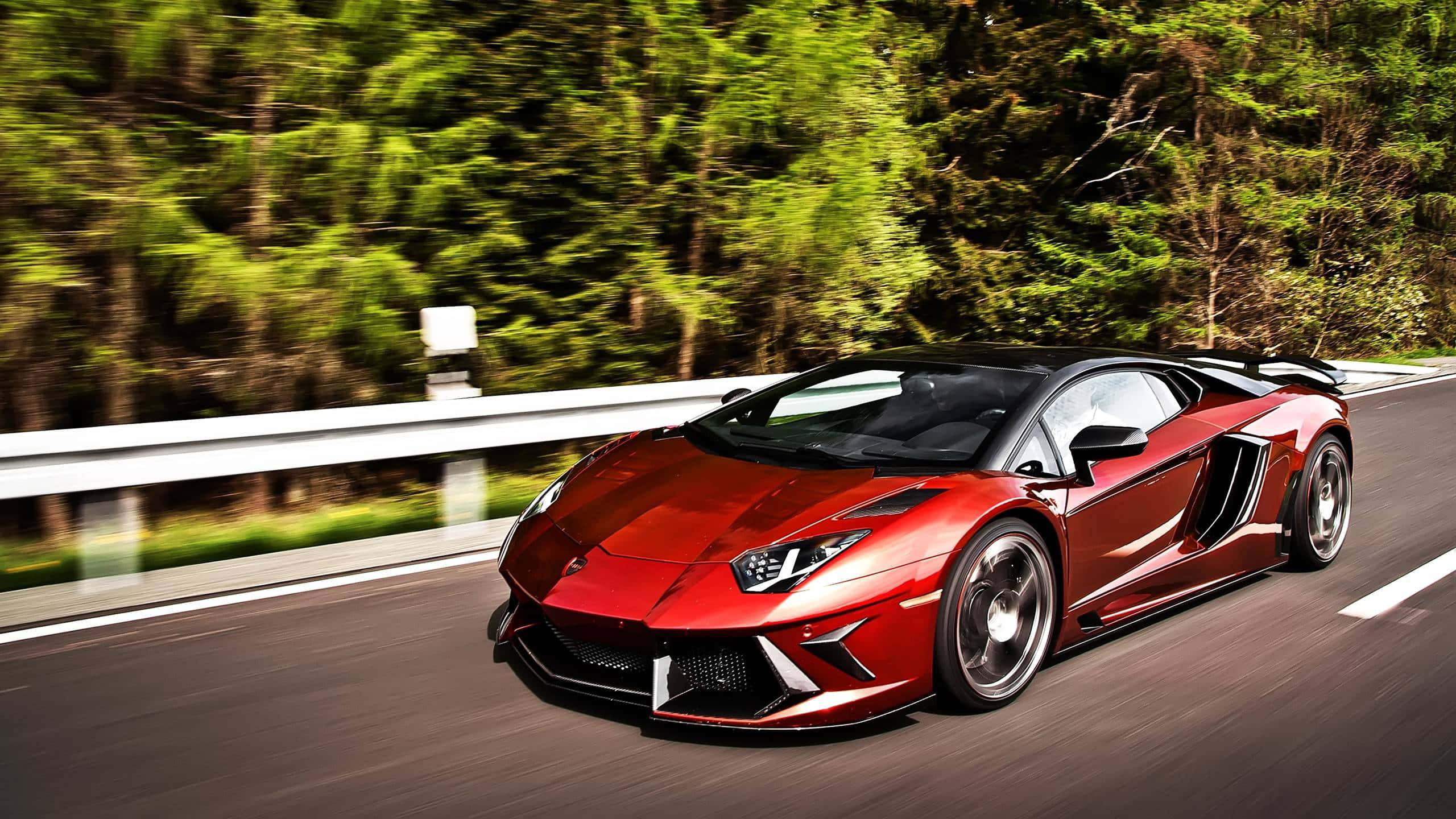 cars 桌布 壁紙 — 一輛鮮紅色的藍寶堅尼 Aventador 在蜿蜒的林間道路上疾馳，周圍帶有動態模糊效果。