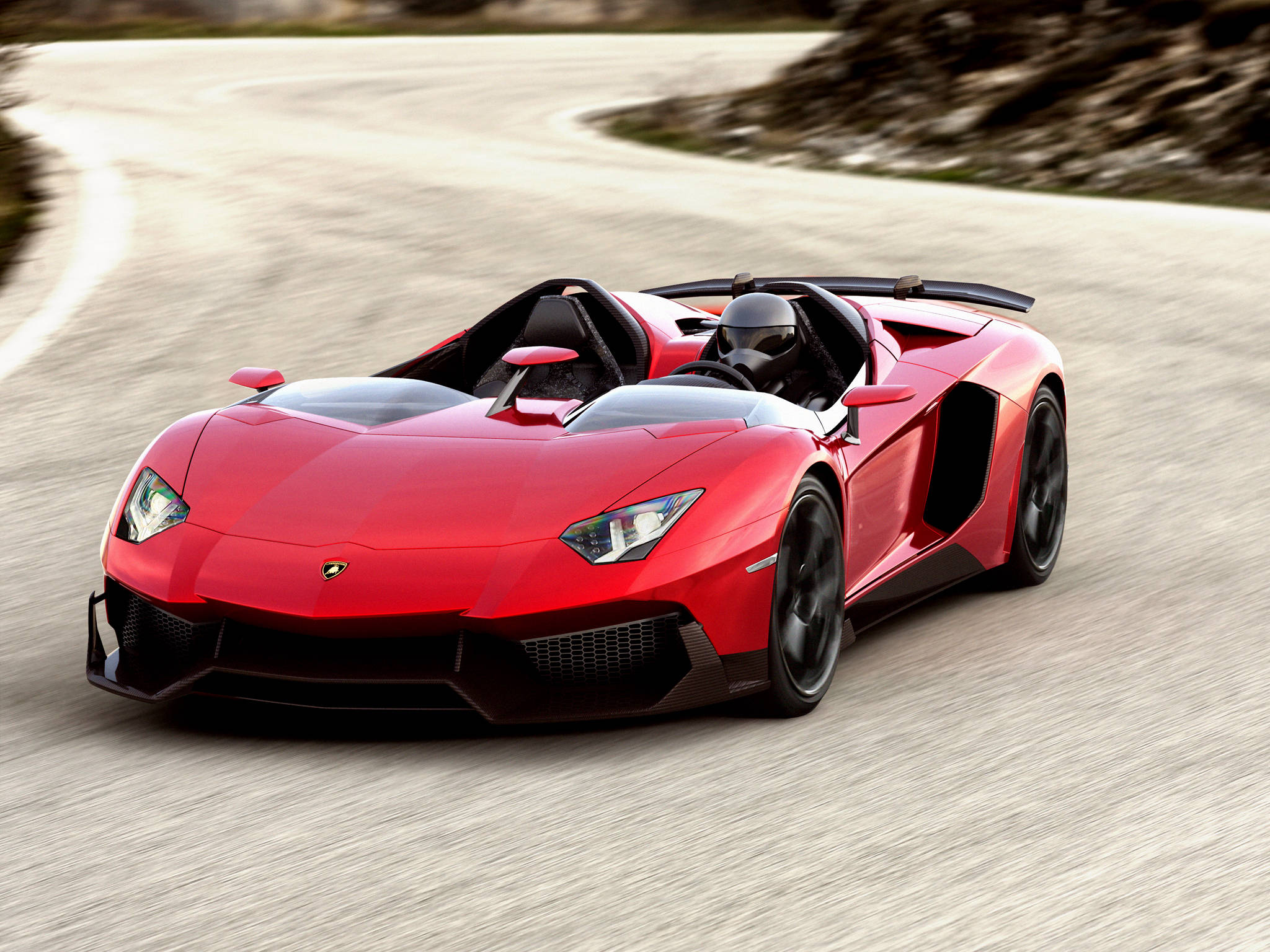 4K 藍寶堅尼 桌布 壁紙 — 一輛鮮紅色的藍寶堅尼 Aventador Roadster 在蜿蜒的山路上奔馳，帶有動態模糊效果。