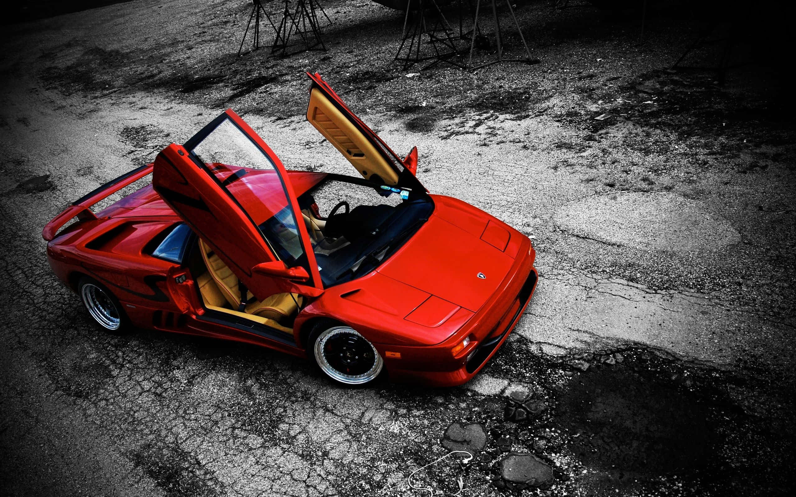 Lamborghini Diablo 桌布 壁紙 — 一輛鮮紅色的藍寶堅尼 Diablo 打開鷗翼車門，戲劇性地停在高對比照明下的破裂瀝青路面上。