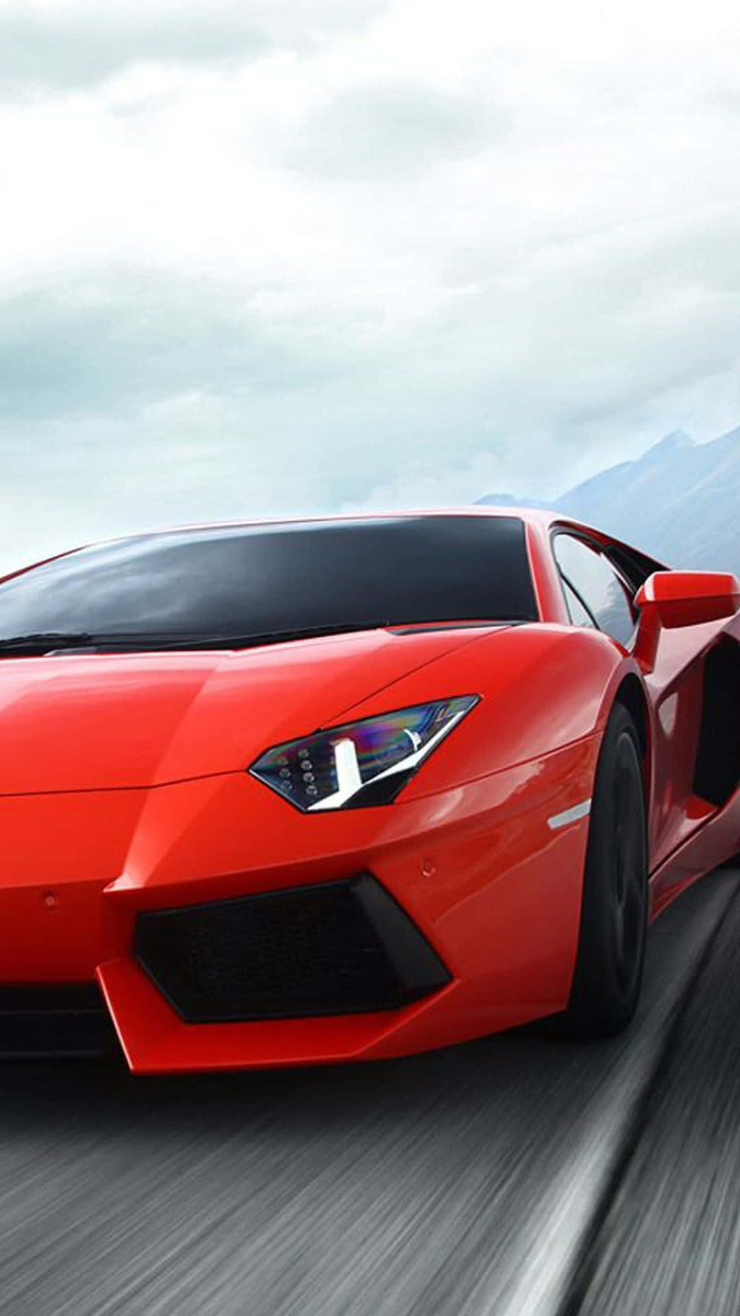 Pixel 3xl Lamborghini 桌布 壁紙 — 一輛鮮紅色的藍寶堅尼在陰天之下沿著山路飛馳，動態模糊強調了速度。