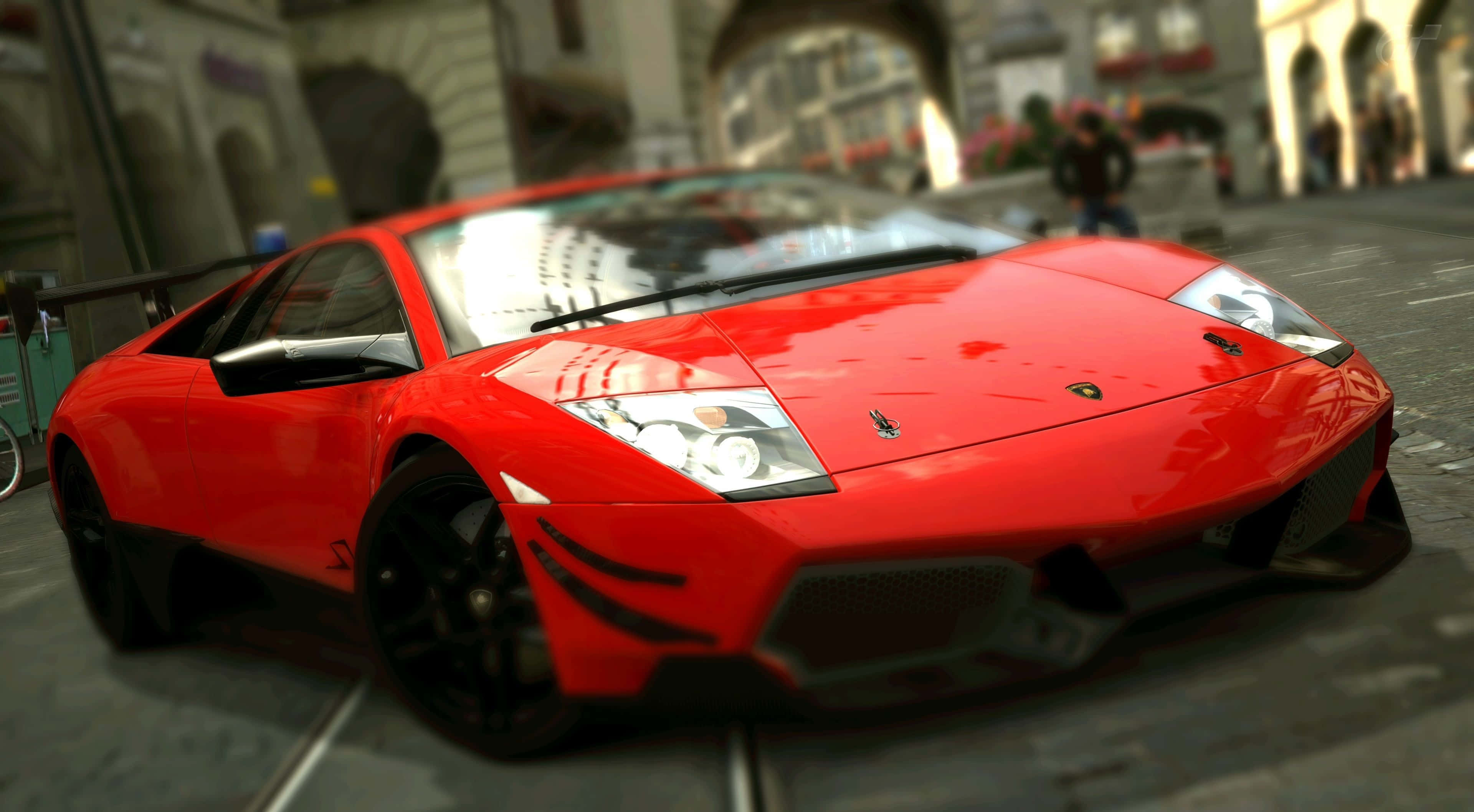 Lamborghini Murciélago 桌布 壁紙 — 一輛鮮紅色的藍寶堅尼跑車在日光下閃耀，行駛在擁有歷史建築的歐洲鵝卵石街道上。