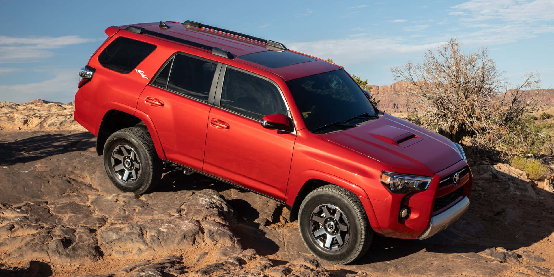 烈日下，紅色豐田4Runner SUV停在岩石沙漠地形上。 — Toyota Supra Mk4 壁紙