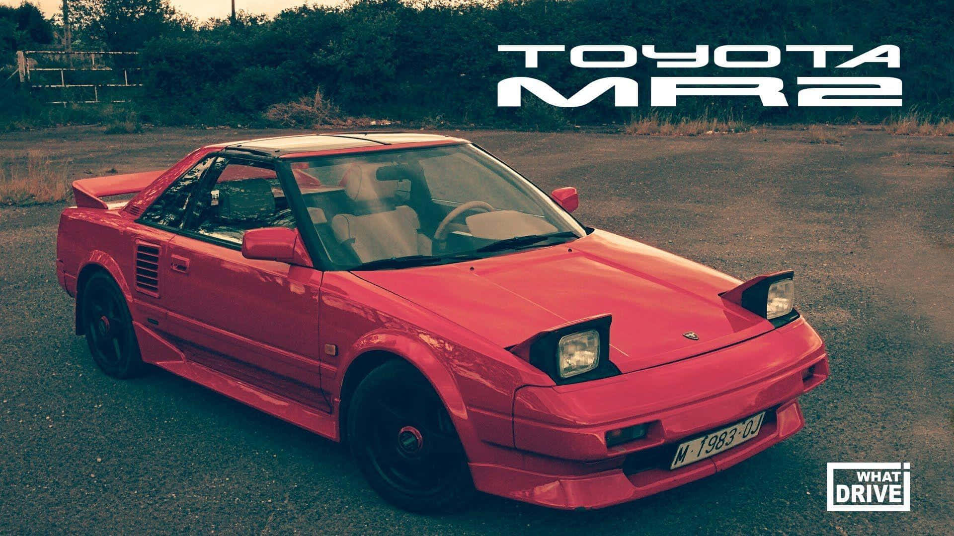 Toyota Mr2 桌布 壁紙 — 一輛鮮紅色的豐田MR2跑車停在碎石上，背景有樹木，在溫暖的日落光線下。