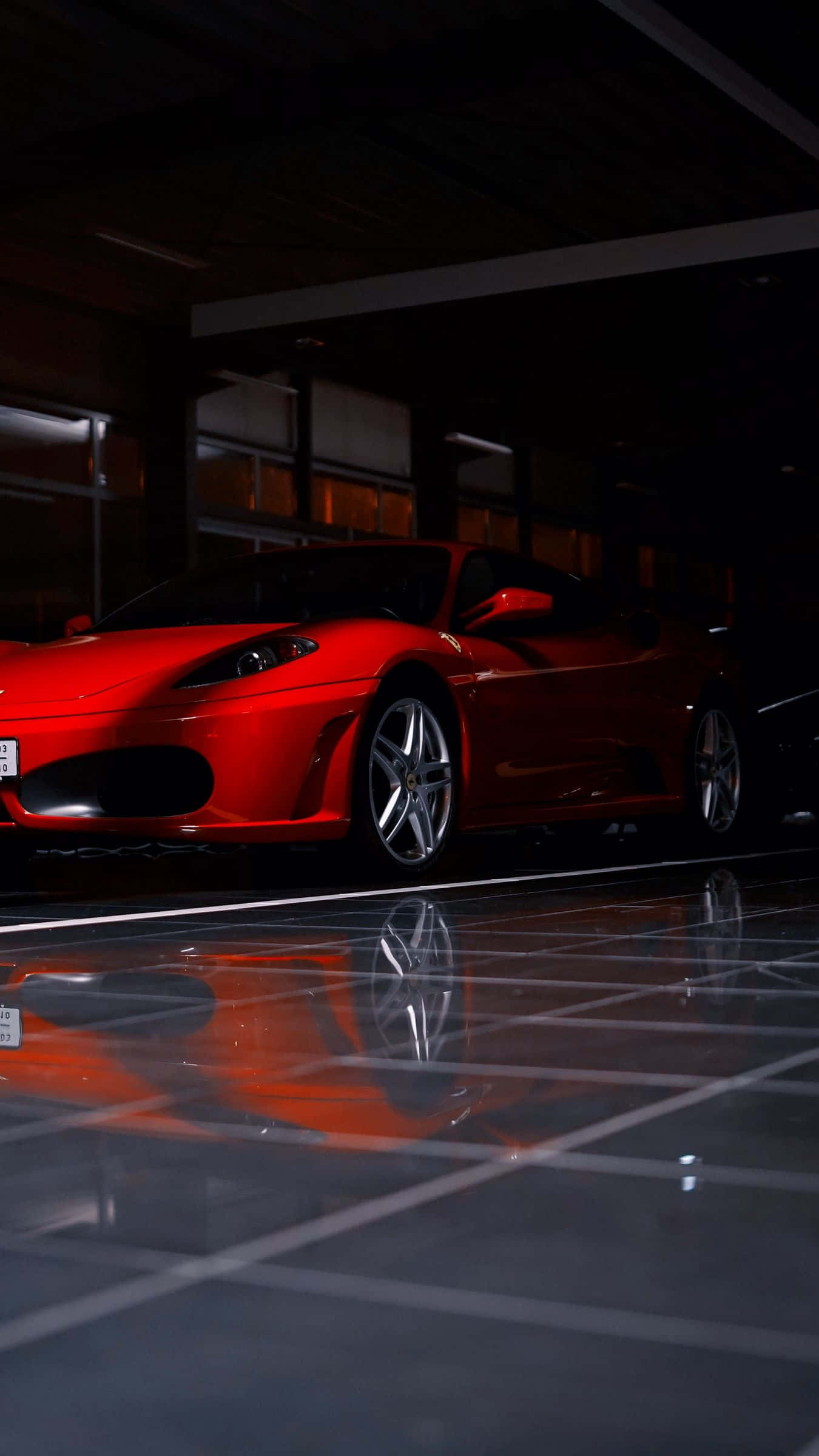 Ferrari F430 桌布 壁紙 — 一輛鮮紅色的跑車在戲劇性的燈光下，在一個鋪有反光瓷磚地板的時尚現代車庫中閃閃發光。