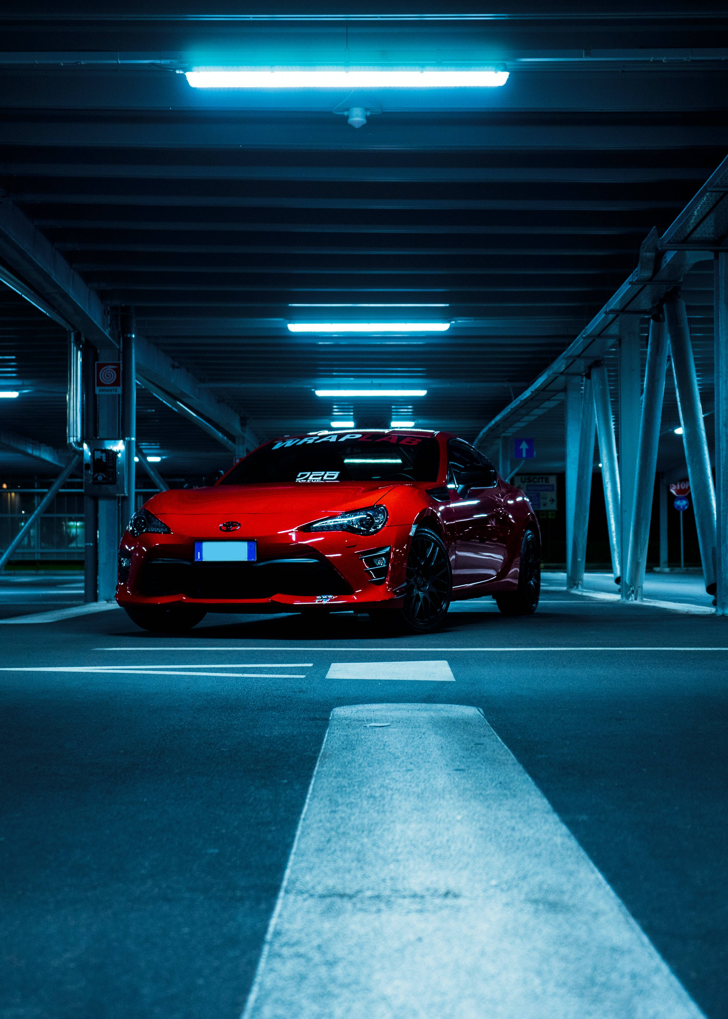 Toyota 桌布 壁紙 — 一輛鮮紅色的跑車在昏暗的地下停車場中，在冰冷的藍色螢光燈下閃閃發光。