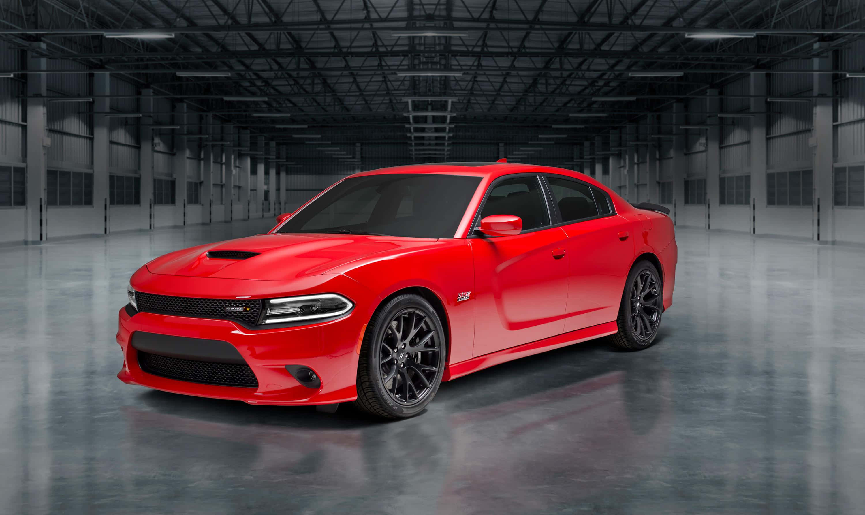 Dodge Charger 桌布 壁紙 — 一輛鮮紅色的道奇 Charger SRT Hellcat 在寬敞的工業倉庫中，於高天花板和混凝土地板上的攝影棚燈光下閃閃發光。