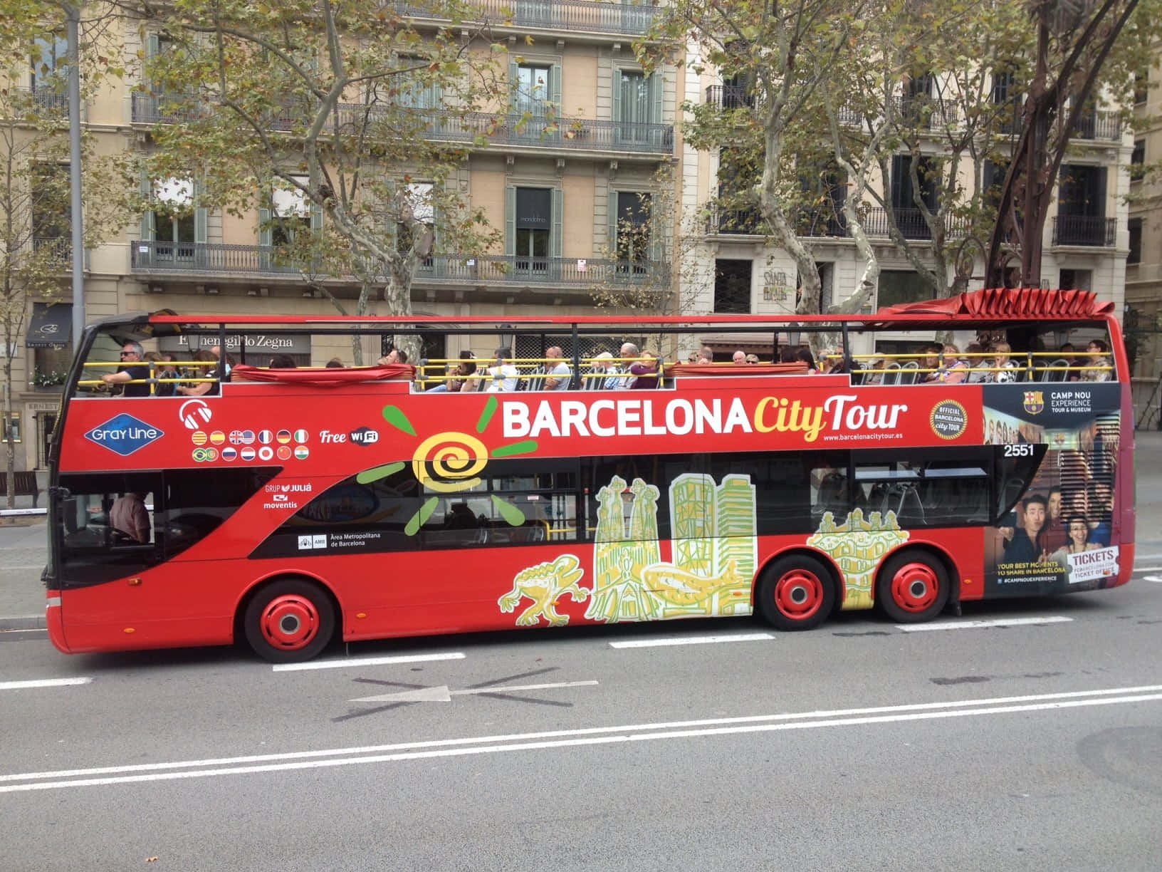 Barcelona 桌布 壁紙 — 一輛鮮紅色的雙層開篷觀光巴士沿著巴塞隆納的林蔭大道行駛，經過歷史建築。