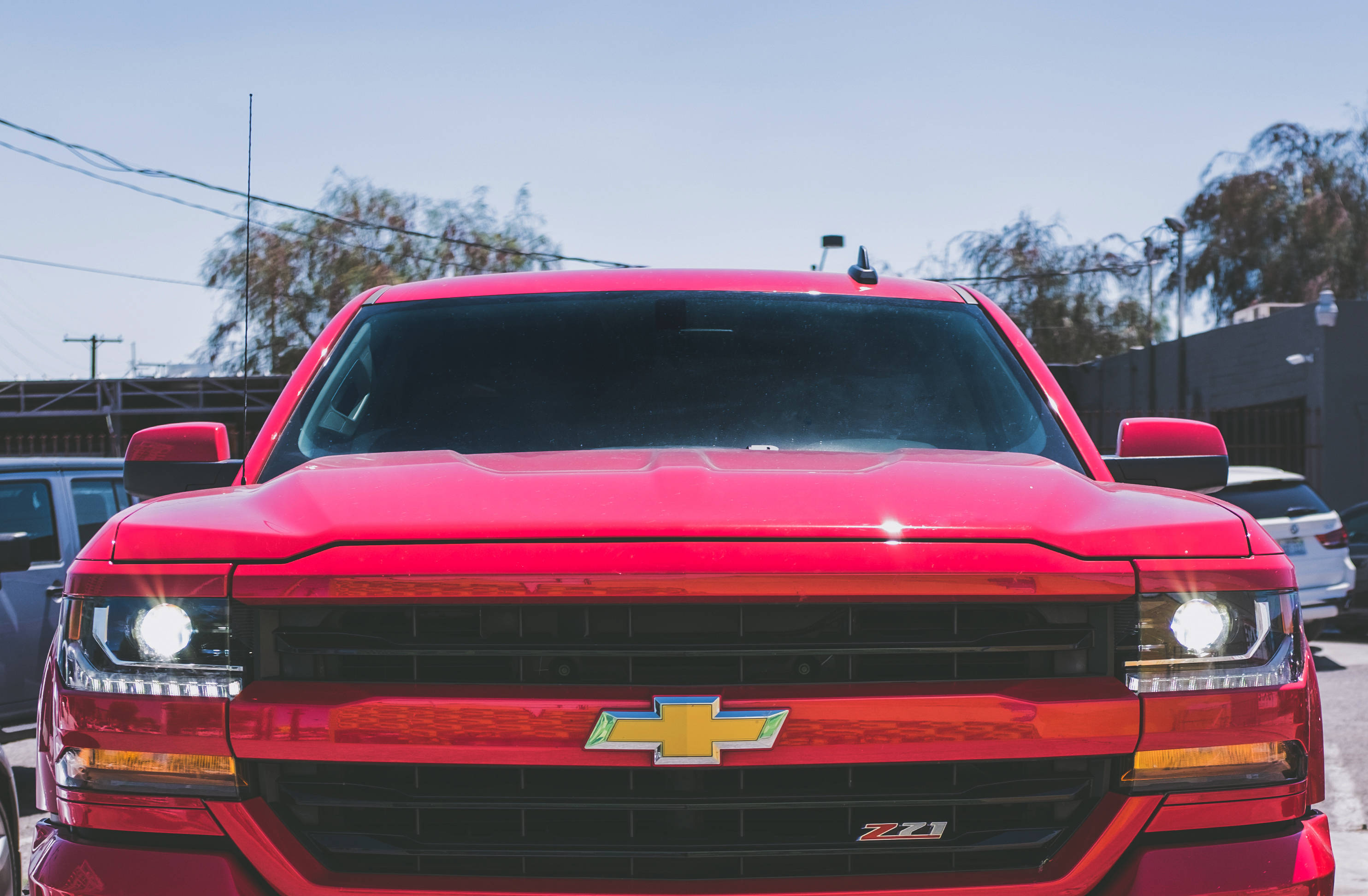 Chevrolet 桌布 壁紙 — 一輛鮮紅色的雪佛蘭 Z71 卡車在明亮的日光下閃閃發光，車頭燈亮起，鍍鉻格柵捕捉陽光。