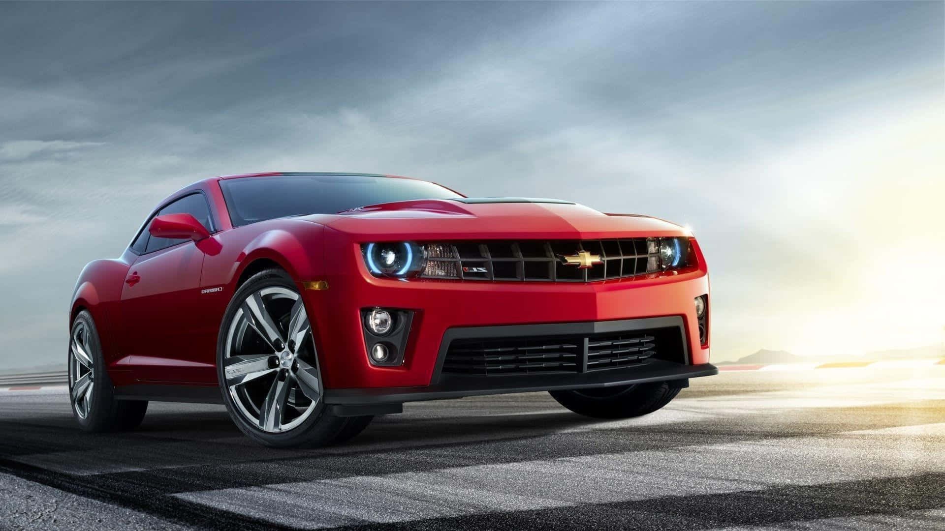 Cool Camaro 桌布 壁紙 — 一輛鮮紅色的雪佛蘭Camaro SS在戲劇性的日落天空下，在空無一人的賽道上閃閃發光。