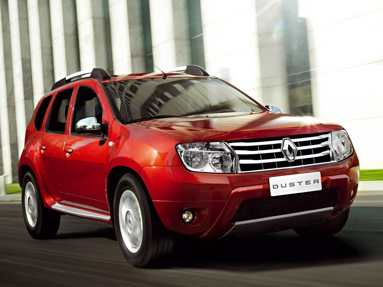 Renault 桌布 壁紙 — 一輛鮮紅色的雷諾 Duster SUV 以動態模糊效果高速駛過一棟現代玻璃建築。