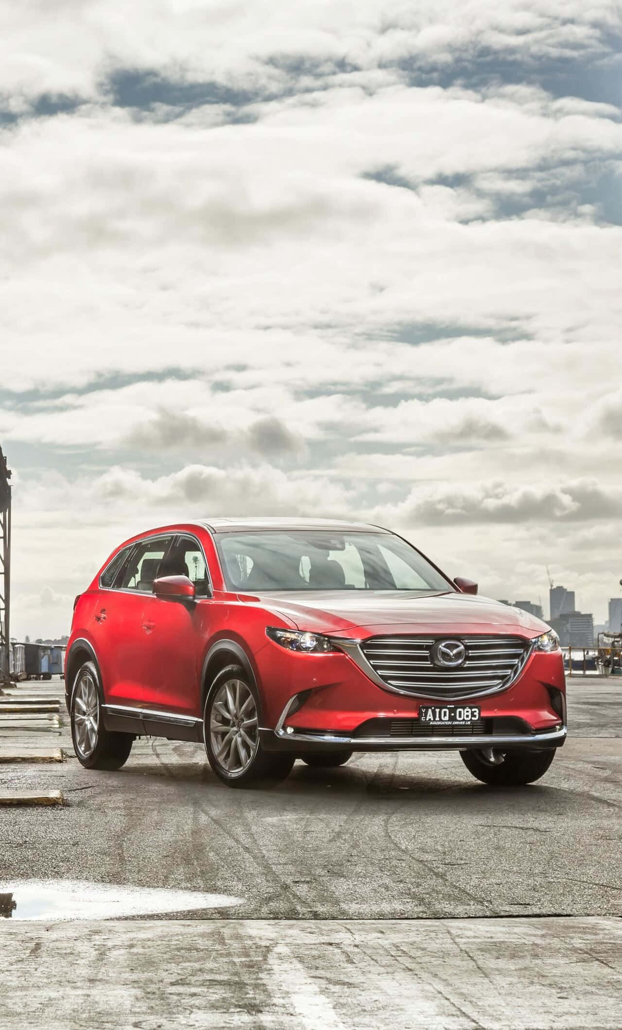 Mazda Cx-9 桌布 壁紙 — 一輛鮮紅色的馬自達CX-5 SUV停在濕漉漉的屋頂上，背後是陰天和遠處的城市天際線。
