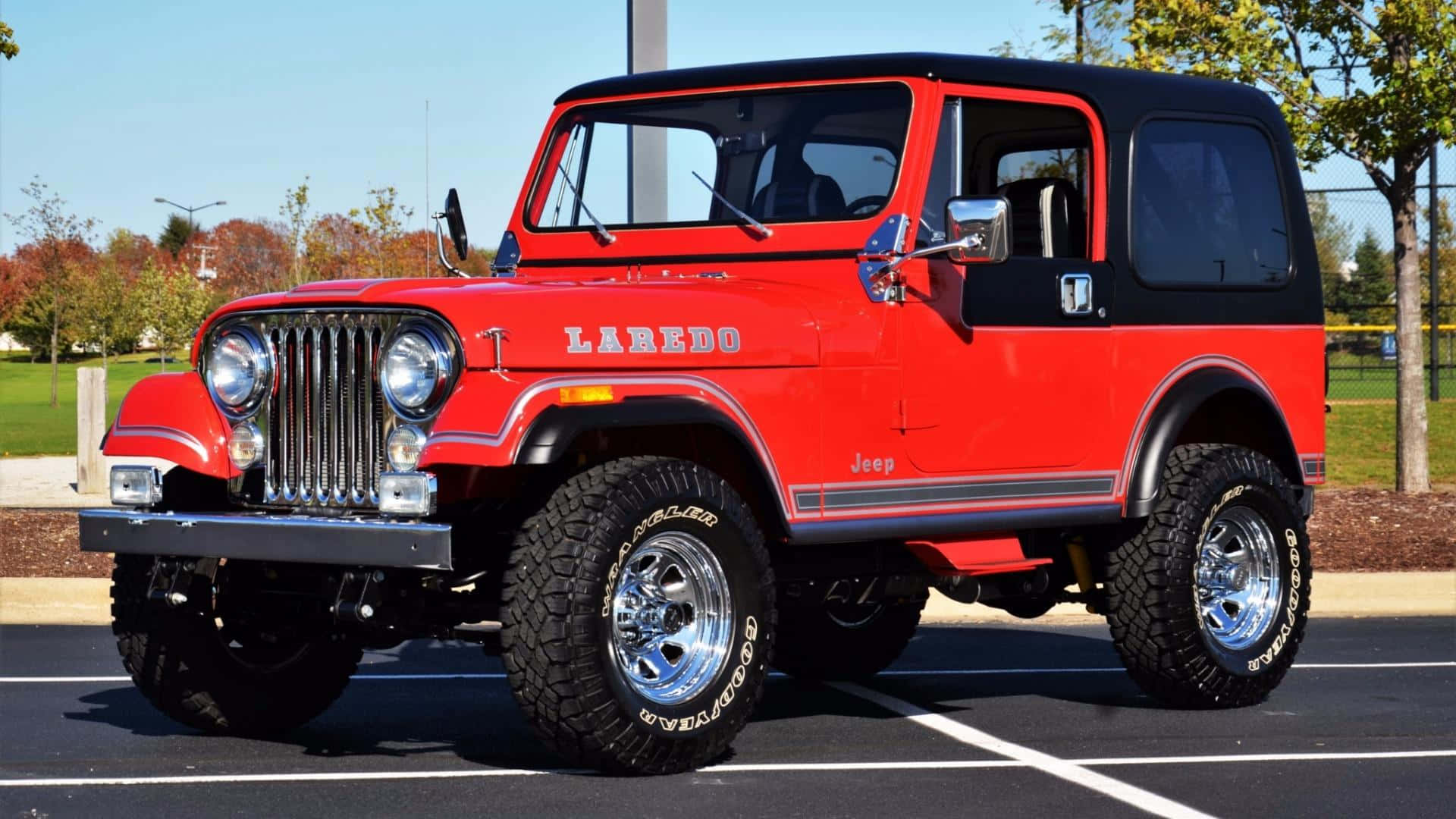 Jeep Cj 桌布 壁紙 — 一輛鮮紅色經典Jeep Laredo，黑色車頂和鍍鉻輪圈，停在陽光明媚的停車場。