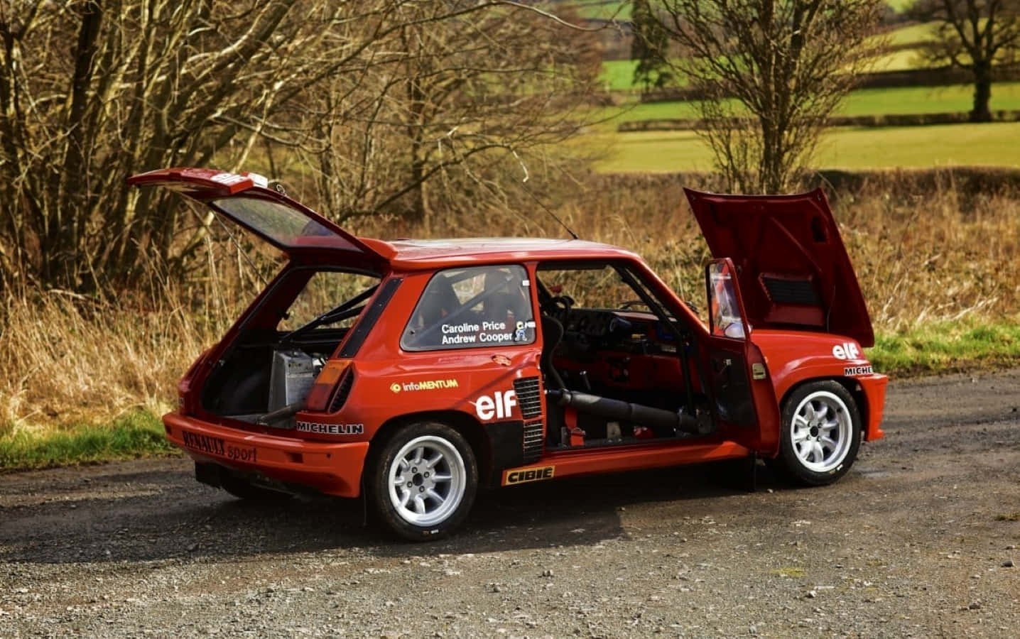 Renault 5 Turbo 桌布 壁紙 — 一輛鮮紅色經典拉力賽車，車門和引擎蓋打開，停放在鄉村碎石路上。