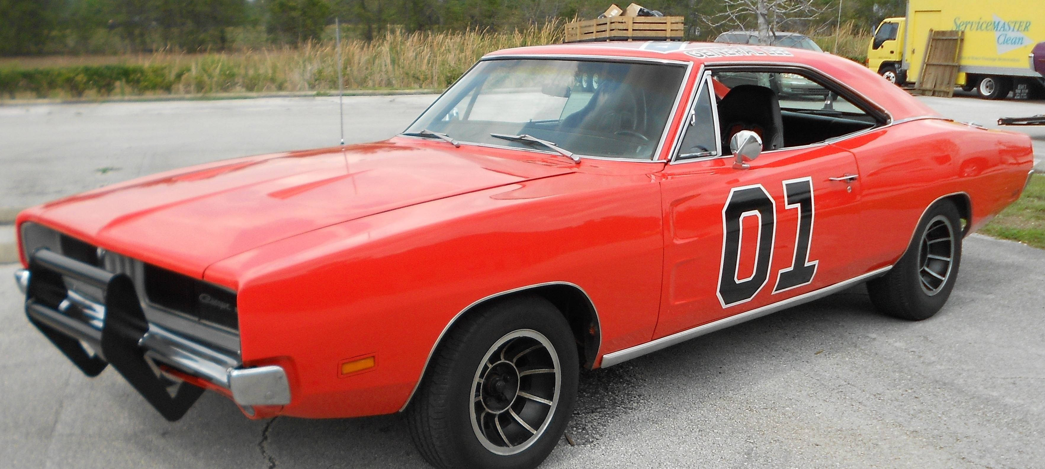 Dukes Of Hazzard 桌布 壁紙 — 一輛鮮紅色經典肌肉車，帶有黑色賽車條紋和醒目的01貼紙，停在裂開的瀝青地上。