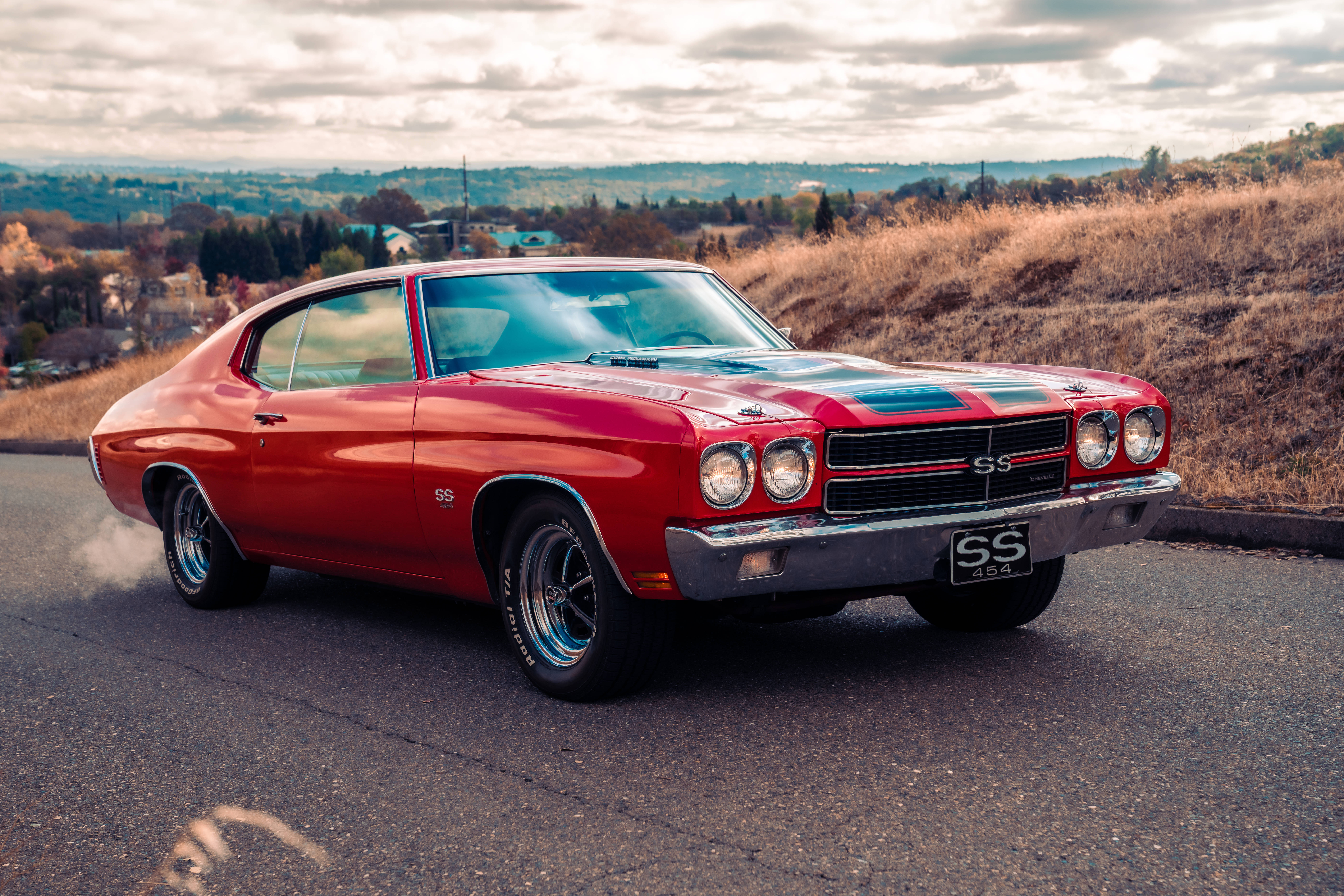 Chevrolet 桌布 壁紙 — 一輛鮮紅色經典肌肉車帶有黑色條紋，停在山坡路上，天空多雲。