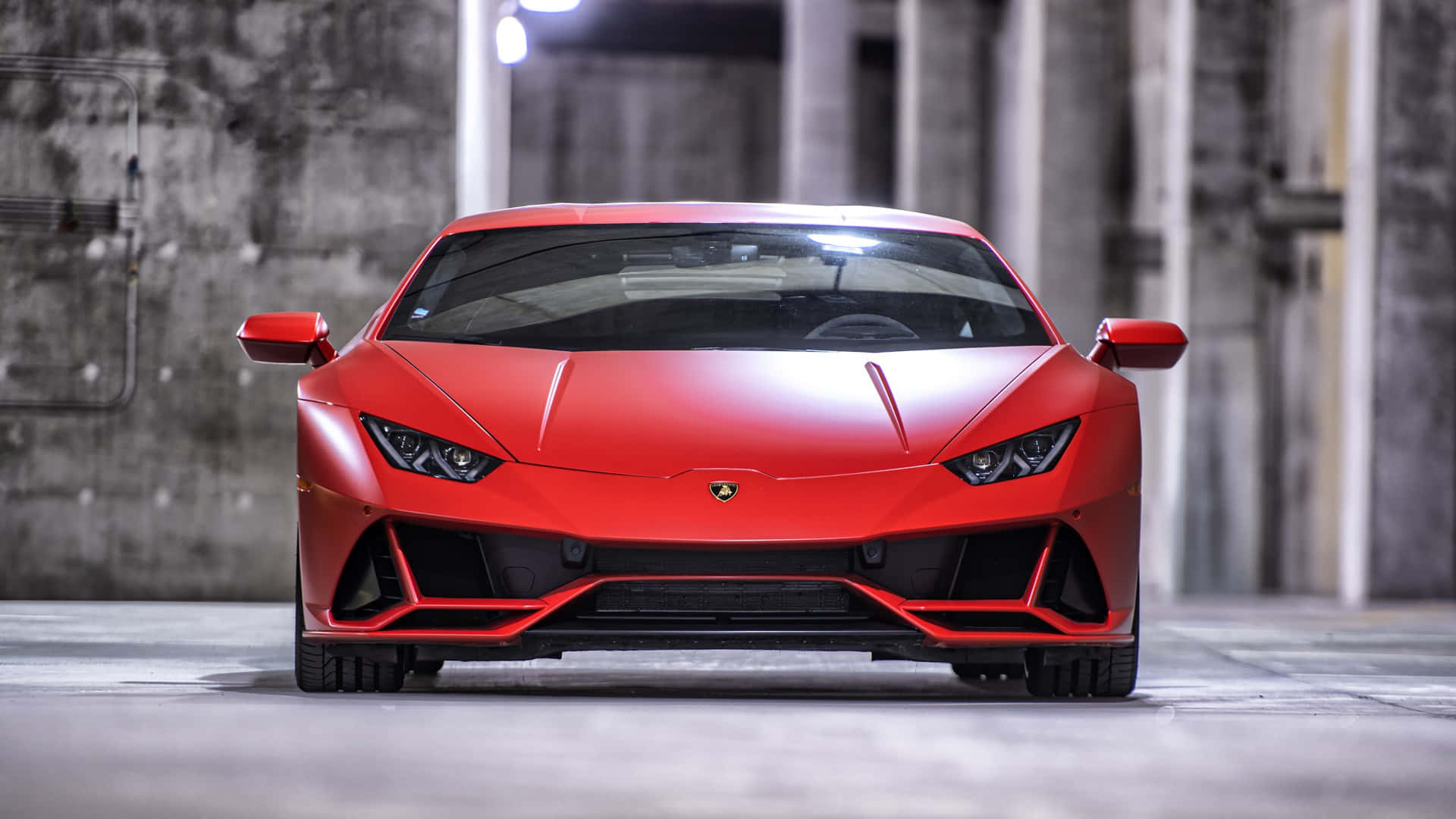 Red Car 桌布 壁紙 — 一輛鮮紅色藍寶堅尼跑車在光線昏暗的混凝土車庫中向前，頭頂有工業照明。