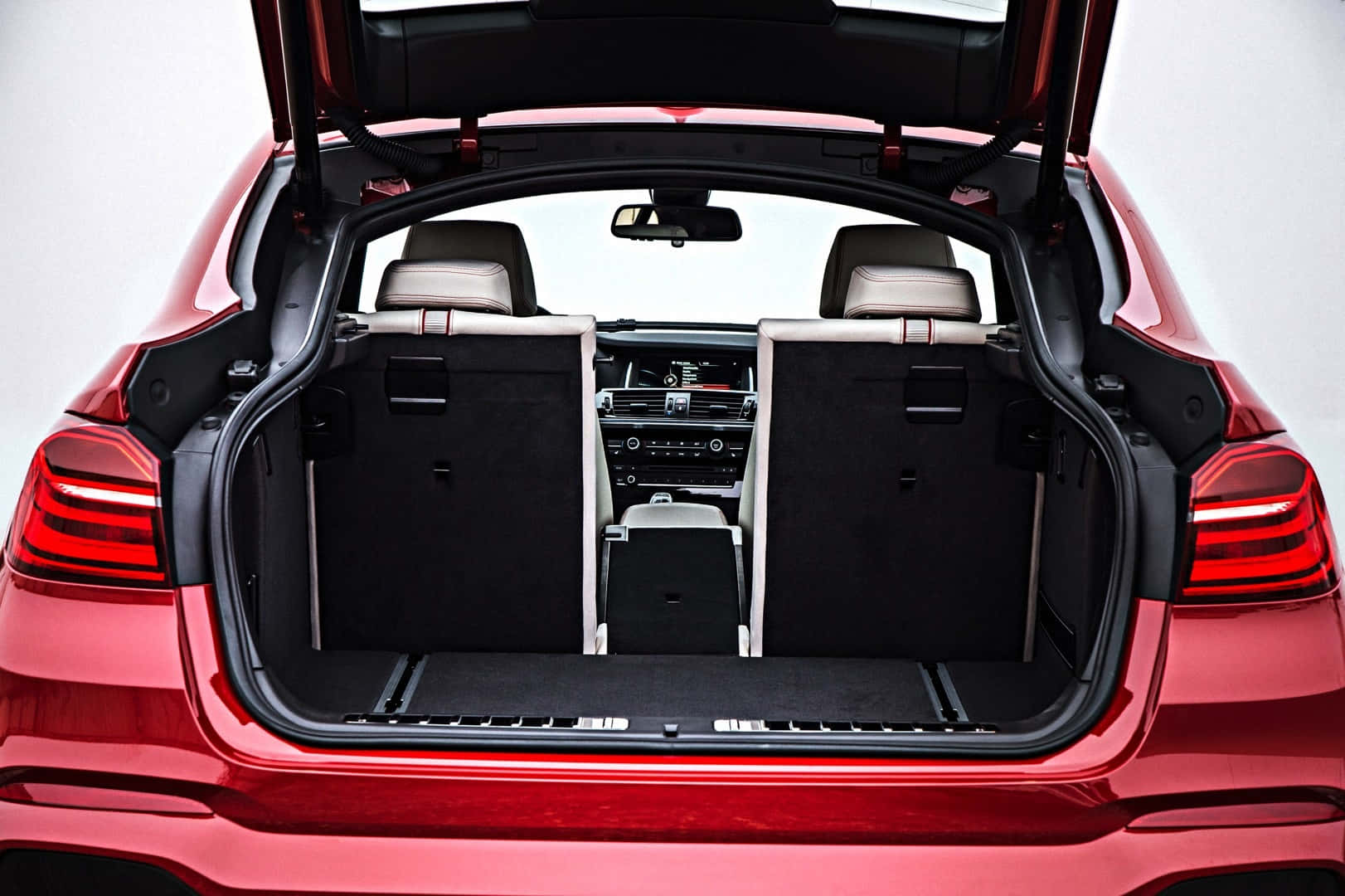 Bmw X4 桌布 壁紙 — 一輛鮮紅色豪華SUV，尾門打開，露出寬敞的黑色貨物區和摺疊的後排座椅。