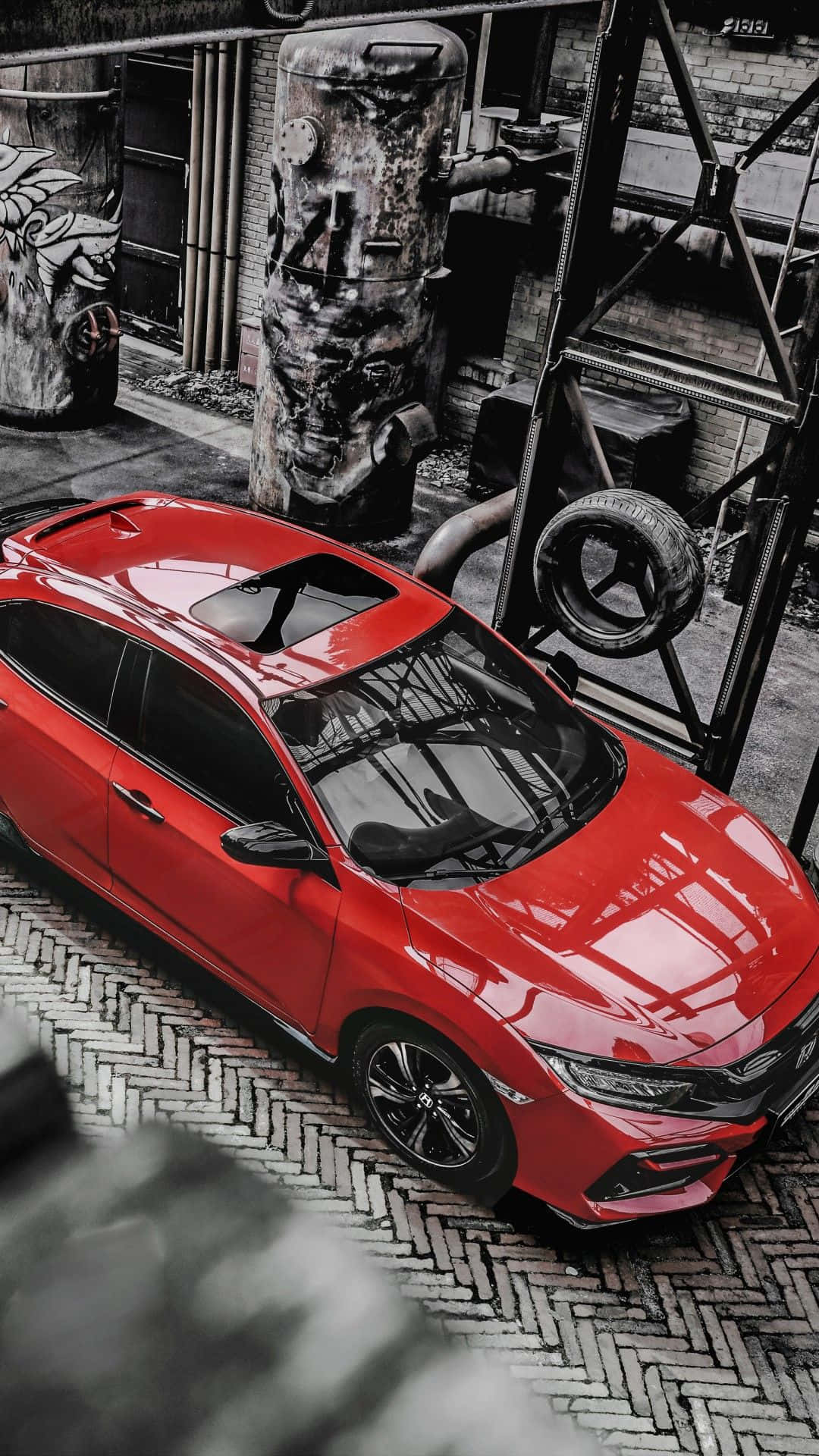Hatchback 桌布 壁紙 — 一輛鮮紅色跑車在工業照明下，於生鏽管道和磚牆之間閃閃發光。