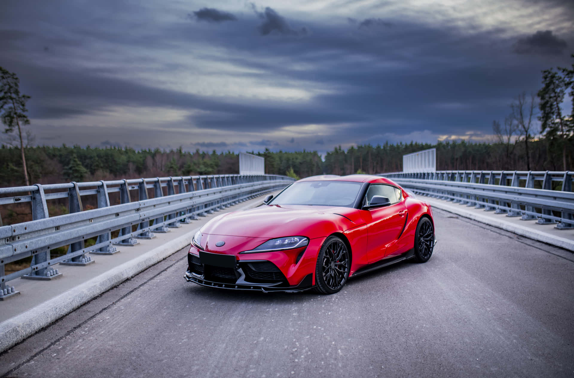 紅色跑車在黃昏時分行駛在橋上，背景為森林。 — Toyota Supra Mk4 壁紙