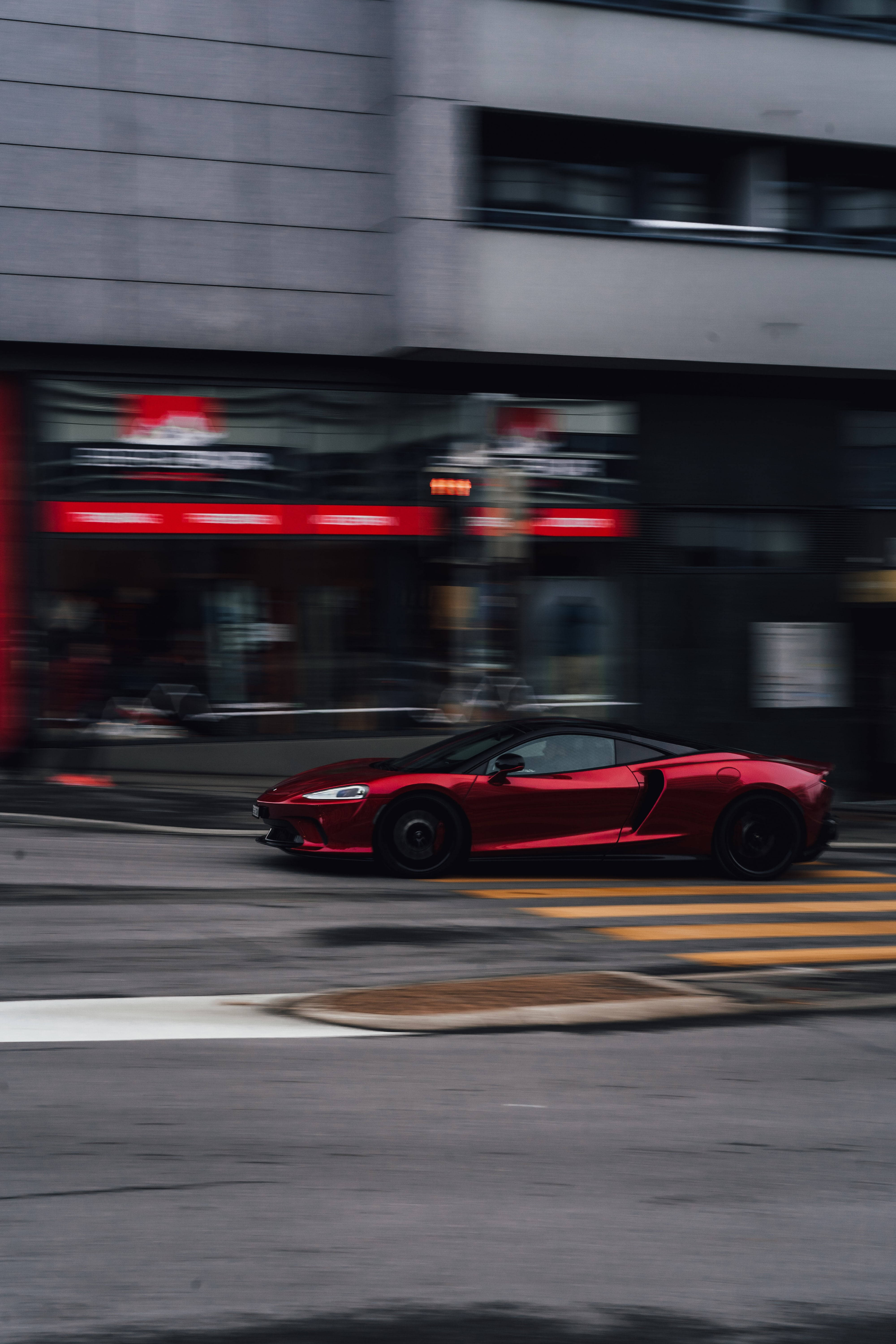speeding car 桌布 壁紙 — 一輛鮮紅色跑車在都市街道上飛馳，動態模糊效果劃過都市背景。