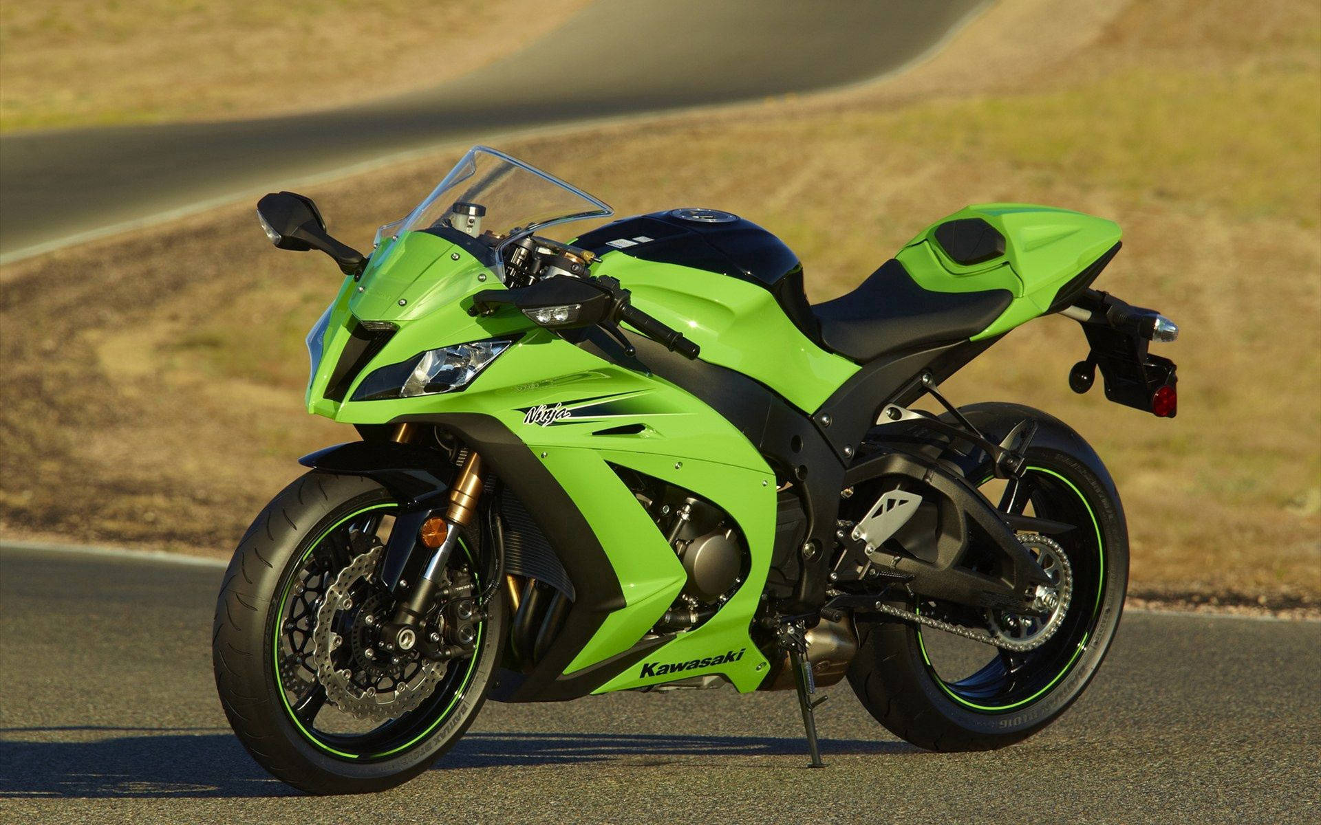 忍者 桌布 壁紙 — 一輛鮮綠色的Kawasaki Ninja機車停泊在彎曲的瀝青路上，背景是乾燥的草山丘。