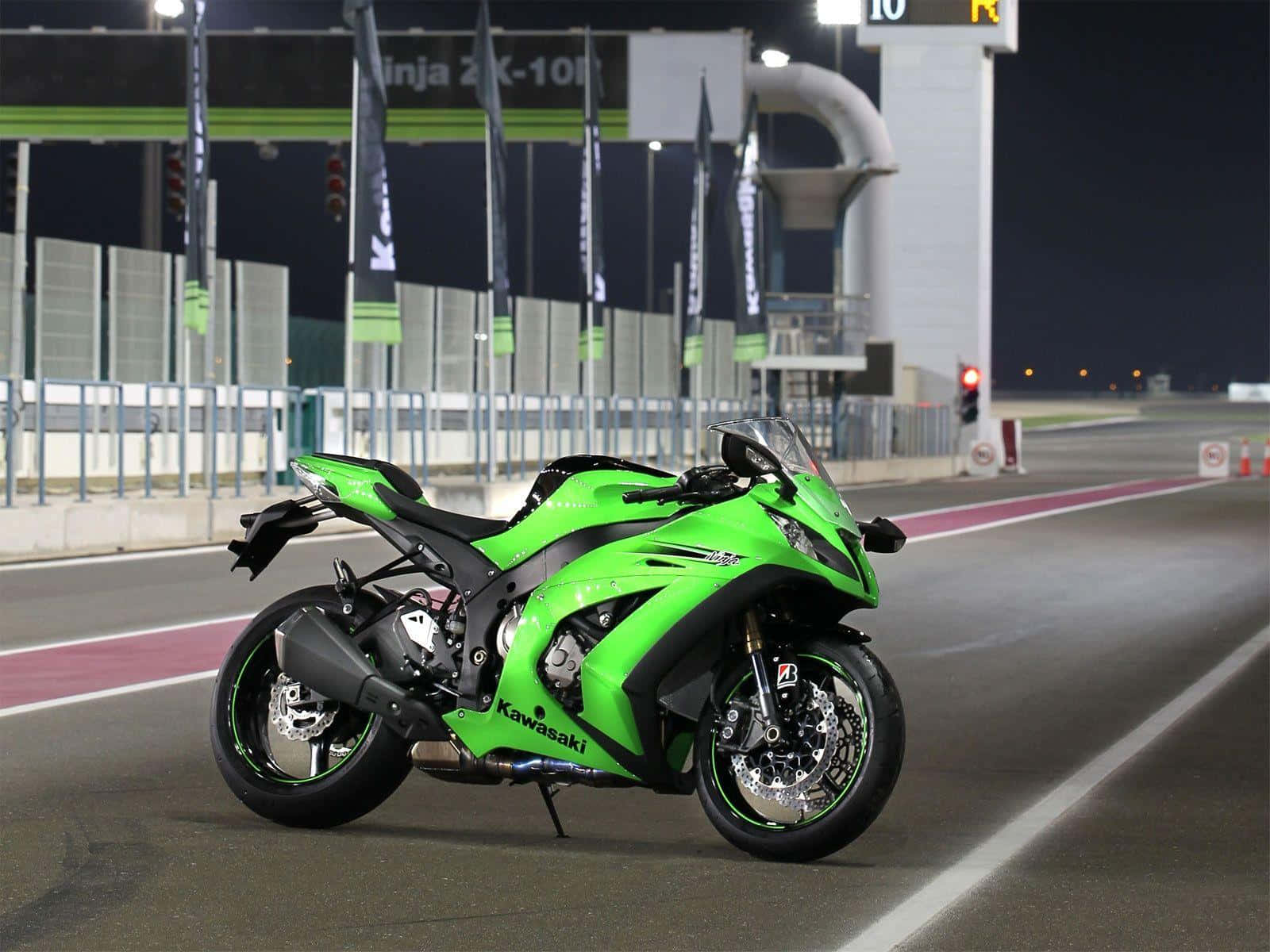 腳踏車 桌布 壁紙 — 一輛鮮綠色的Kawasaki Ninja ZX-10R摩托車在夜間停在賽車場上，在明亮的人造燈光下。