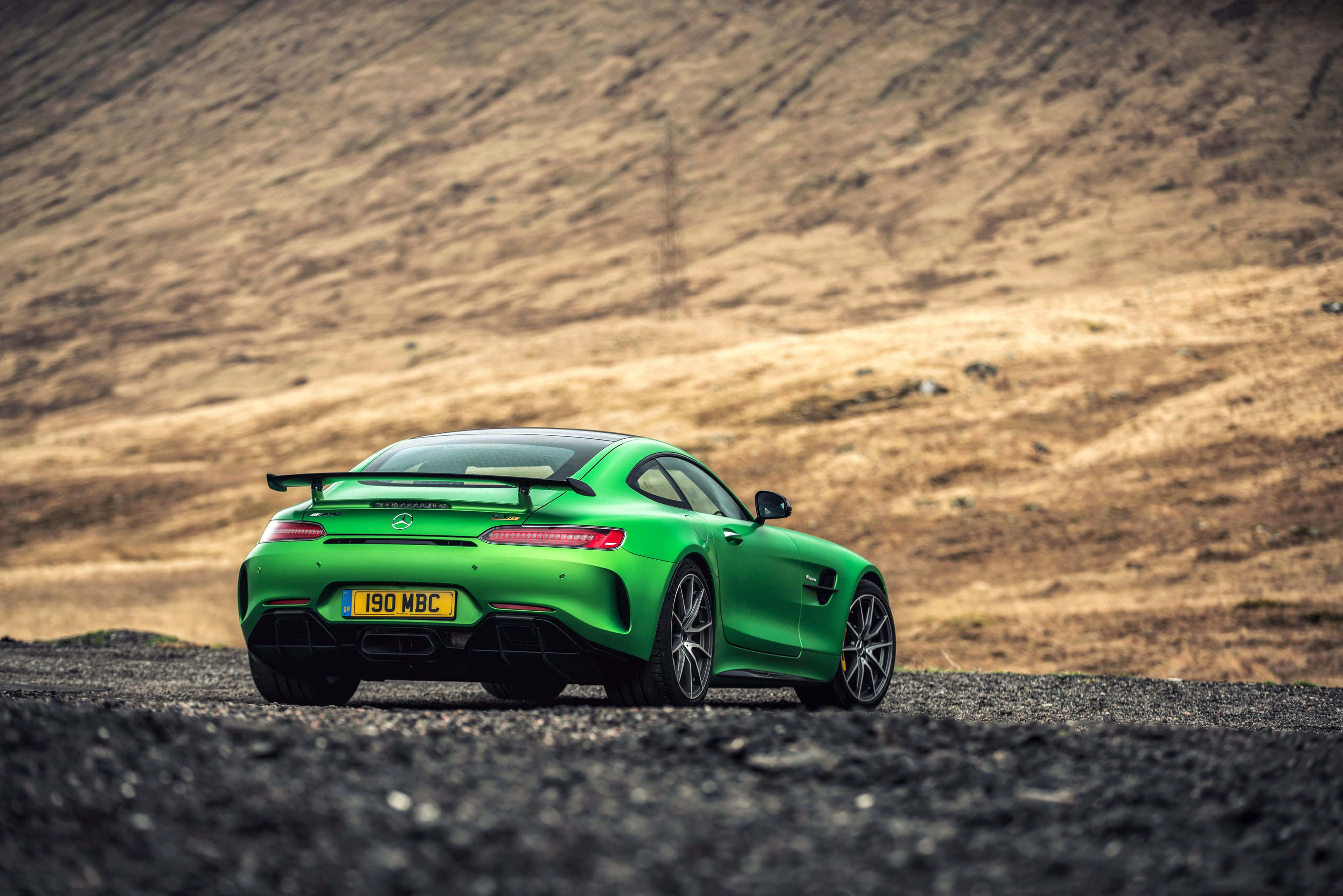 Mercedes 桌布 壁紙 — 一輛鮮綠色的Mercedes-AMG GT R跑車停泊在碎石路上，背景是乾燥起伏的山丘。