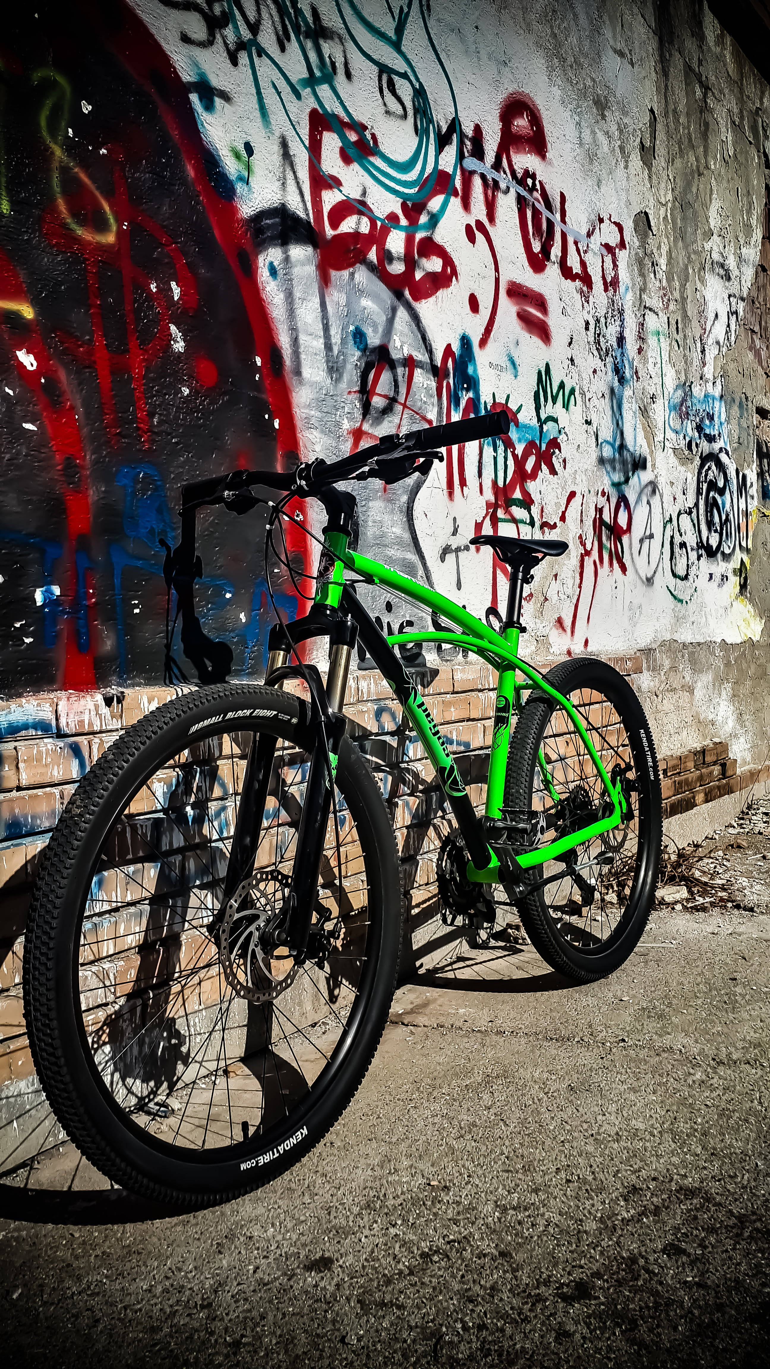 Mountain Bike 桌布 壁紙 — 一輛鮮綠色的登山自行車靠在一條城市後巷的塗鴉混凝土牆上。