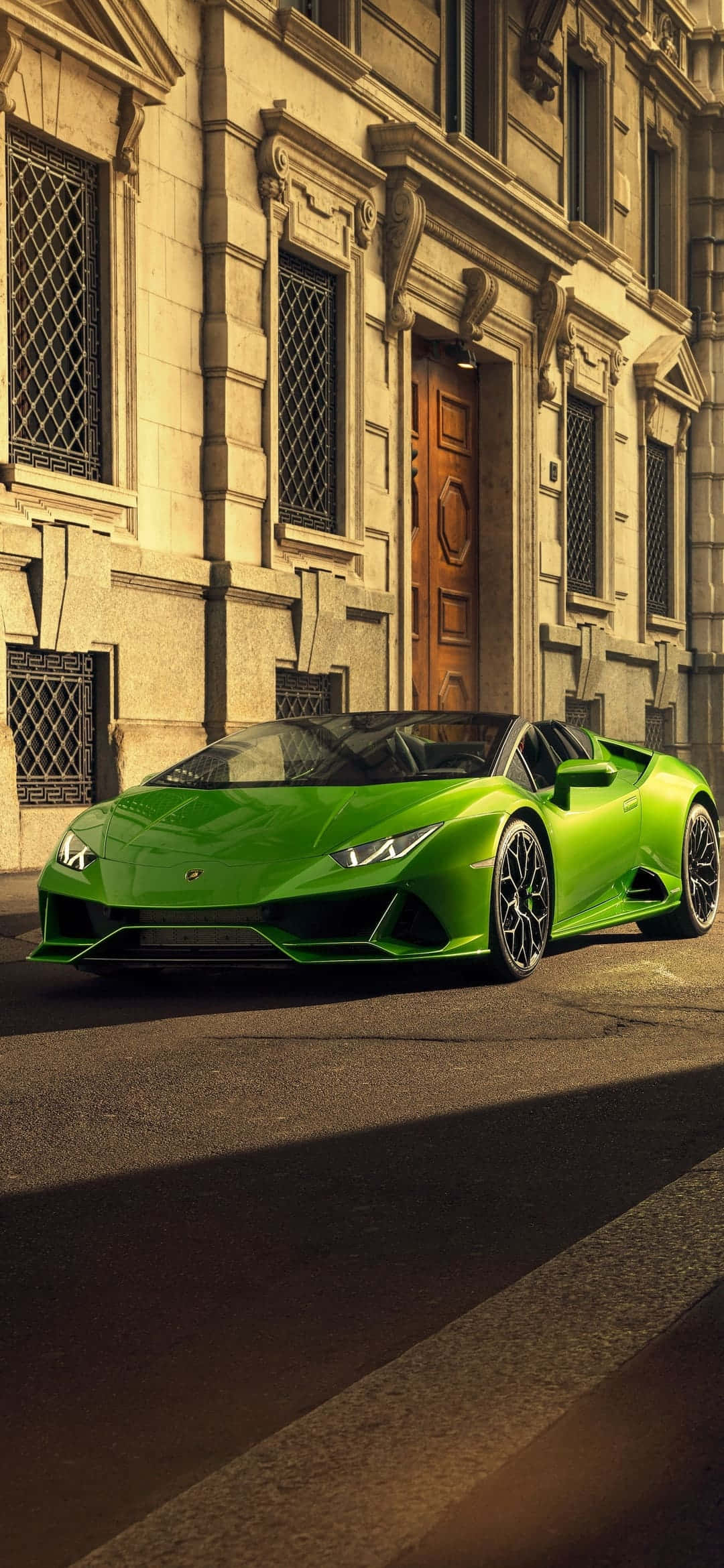 Pixel 3xl Lamborghini 桌布 壁紙 — 一輛鮮綠色的藍寶堅尼 Huracán Spyder 停泊在陽光明媚的街道上，前方是一座宏偉的石造建築，帶有華麗的窗戶和木門。